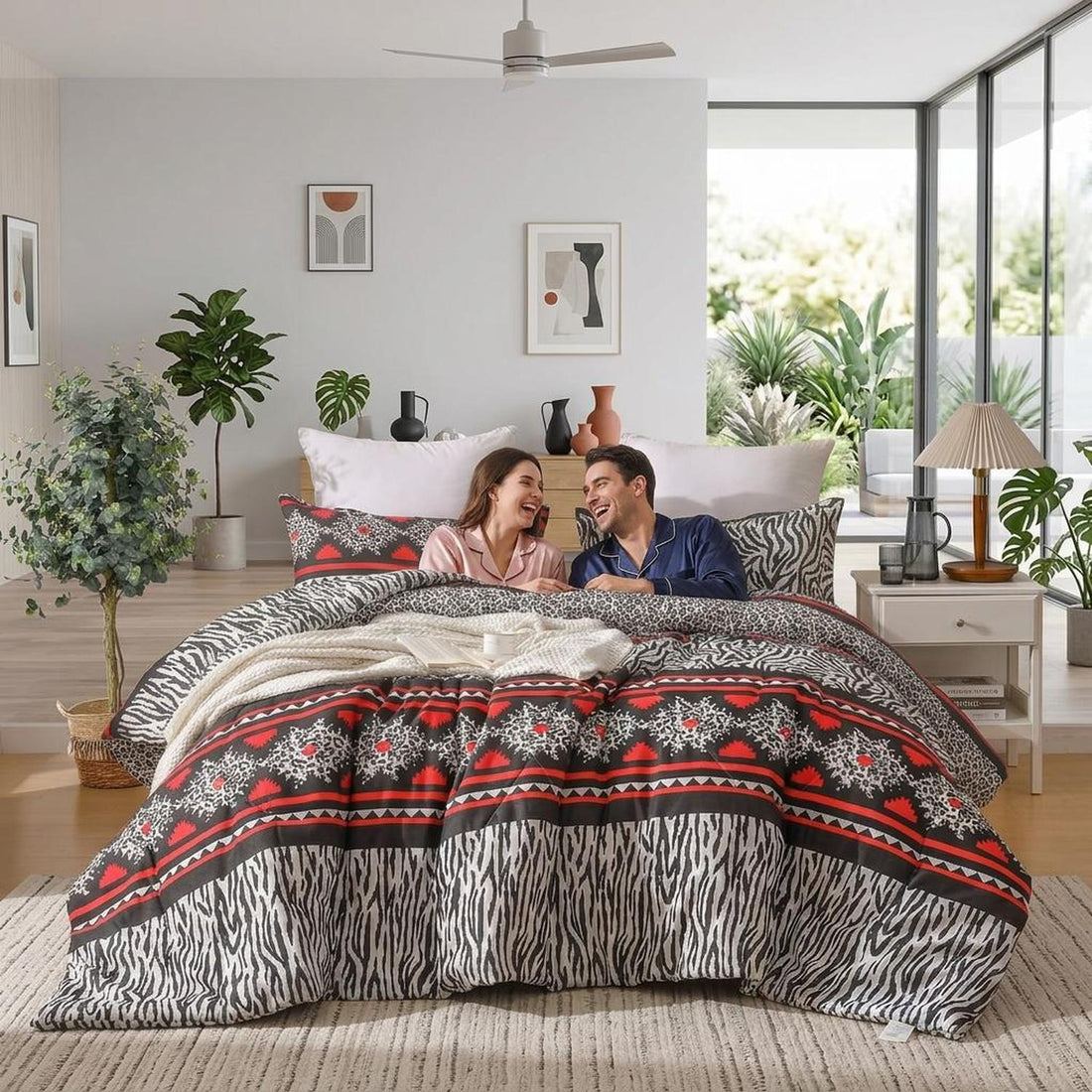 Couple laughing on a bed with a red, black, and white zebra print quilted comforter set.