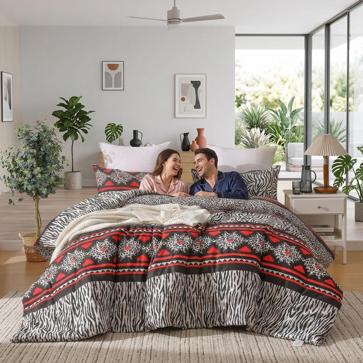 Couple laughing on a bed with a red, black, and white zebra print quilted comforter set.