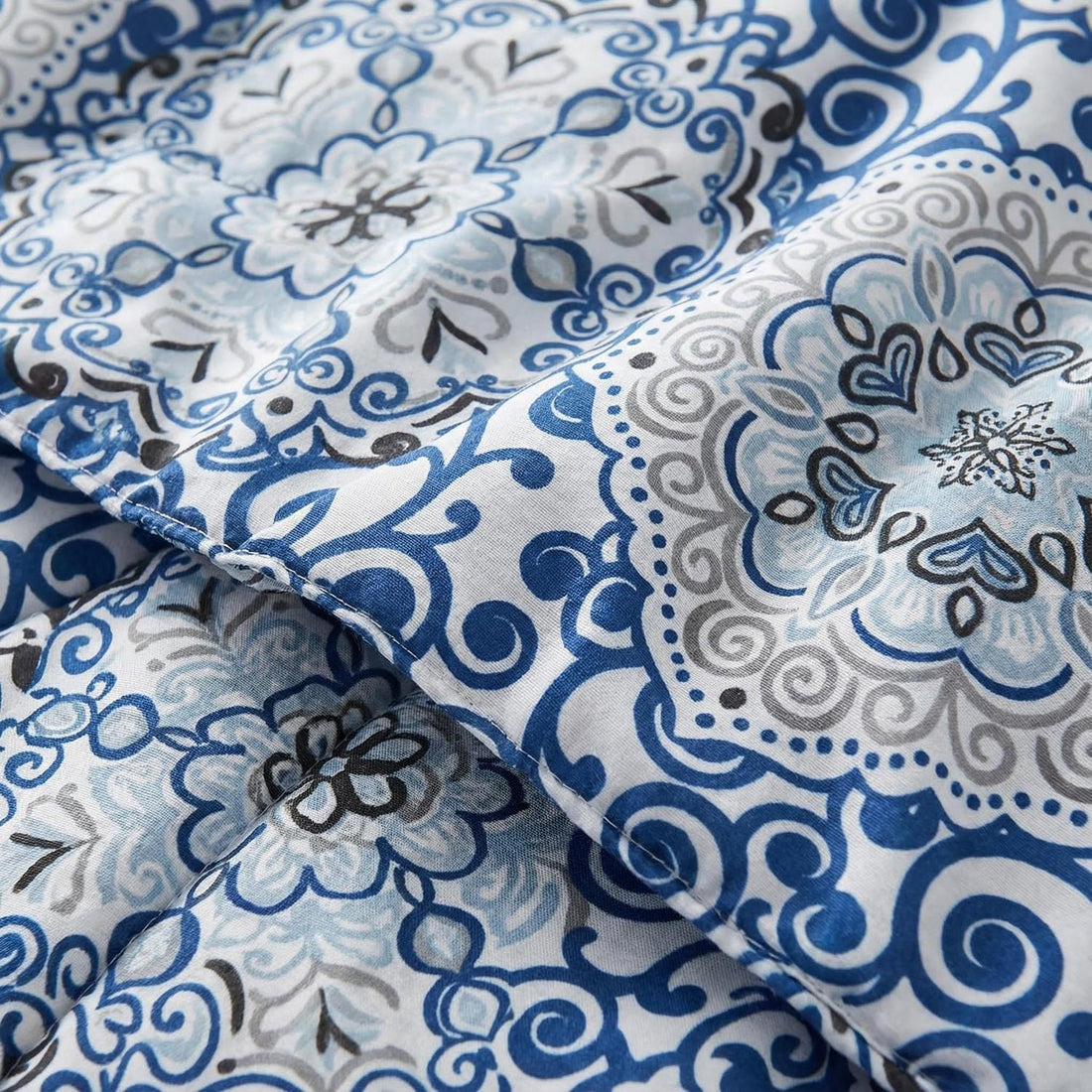 Aztec Blue reversible comforter set with a mother and child on a bed in a bright bedroom.