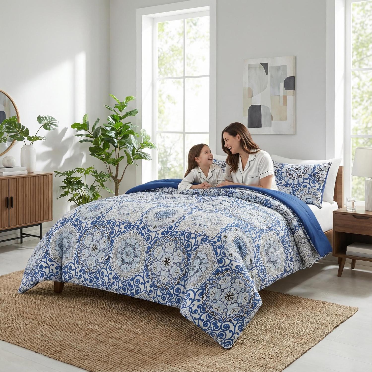 Aztec Blue reversible comforter set with a mother and child on a bed in a bright bedroom.