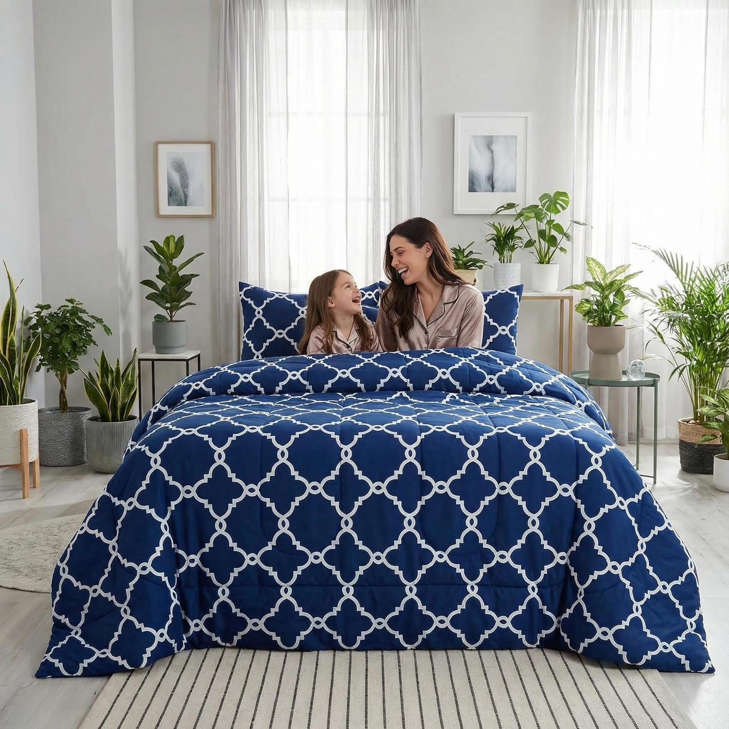 Navy blue reversible comforter set with white quatrefoil pattern on a bed with a woman and child.