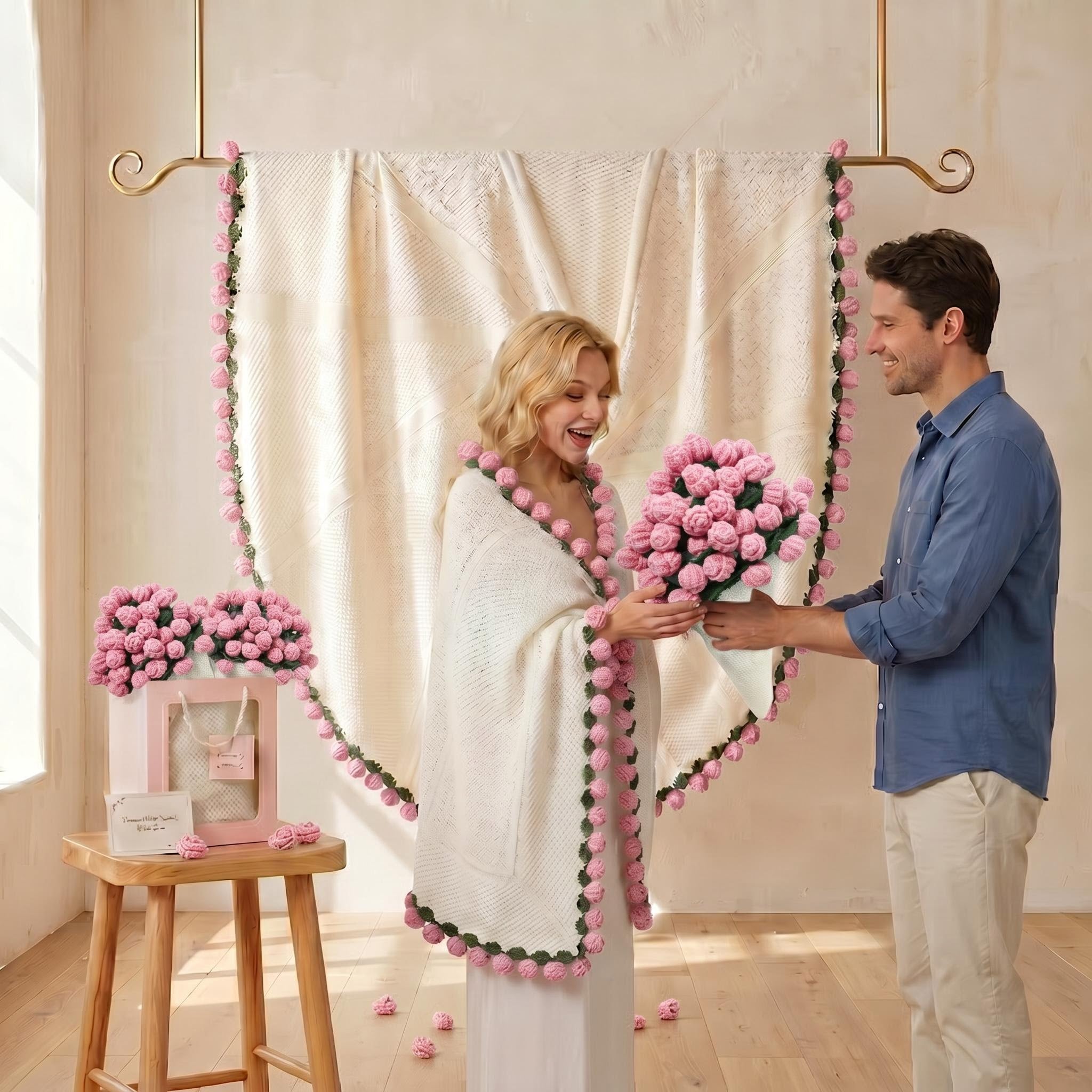Woman in a white crochet blanket with pink rose trim receiving a pink rose bouquet from a man.
