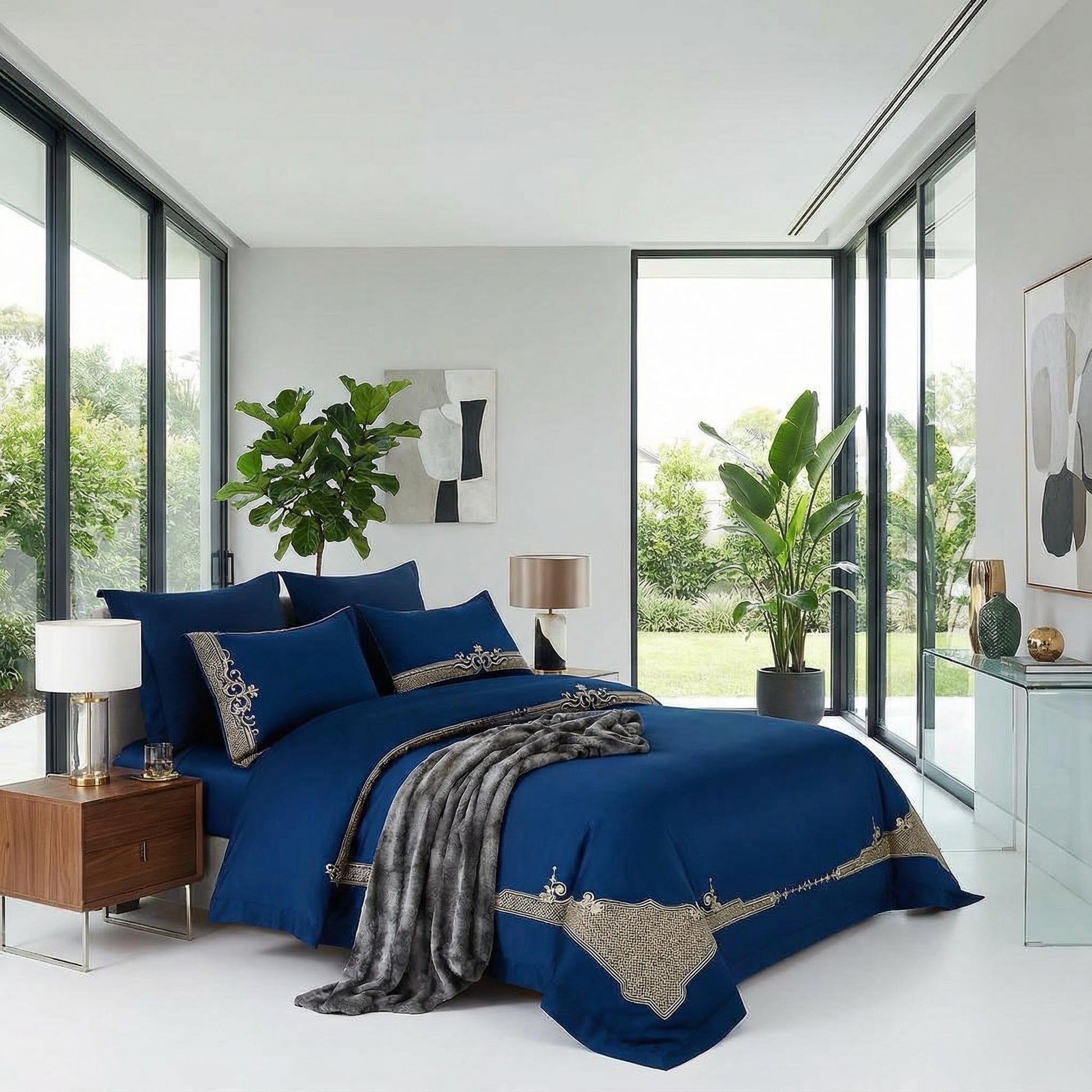 Royal blue cotton bedding set with elegant gold embroidery, a soft gray throw, and matching pillows in a modern bedroom.