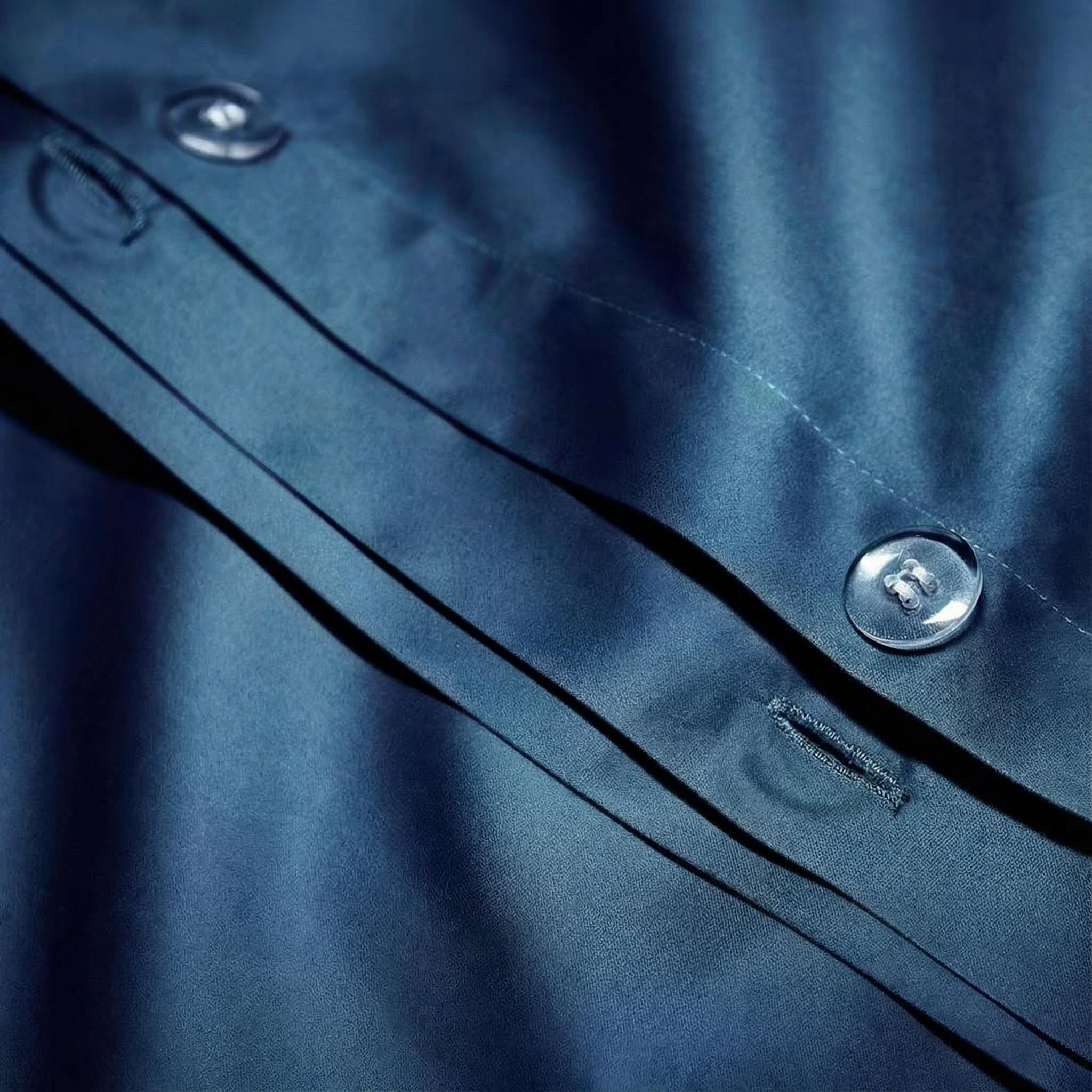 Close-up of a royal blue cotton duvet cover with clear buttons and subtle fabric folds.