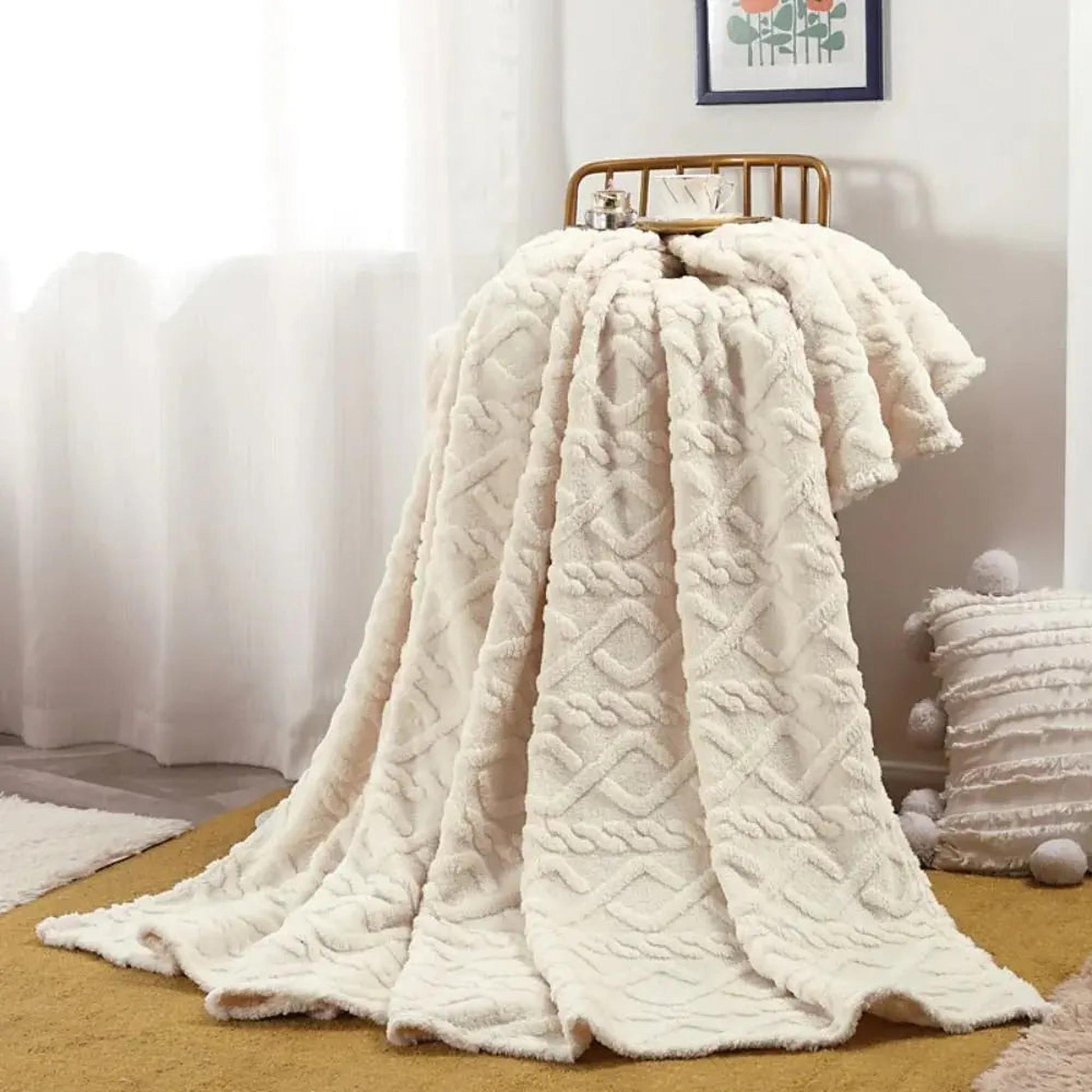 Cream ruched faux fur throw blanket draped over a gold chair, with a textured pillow nearby.