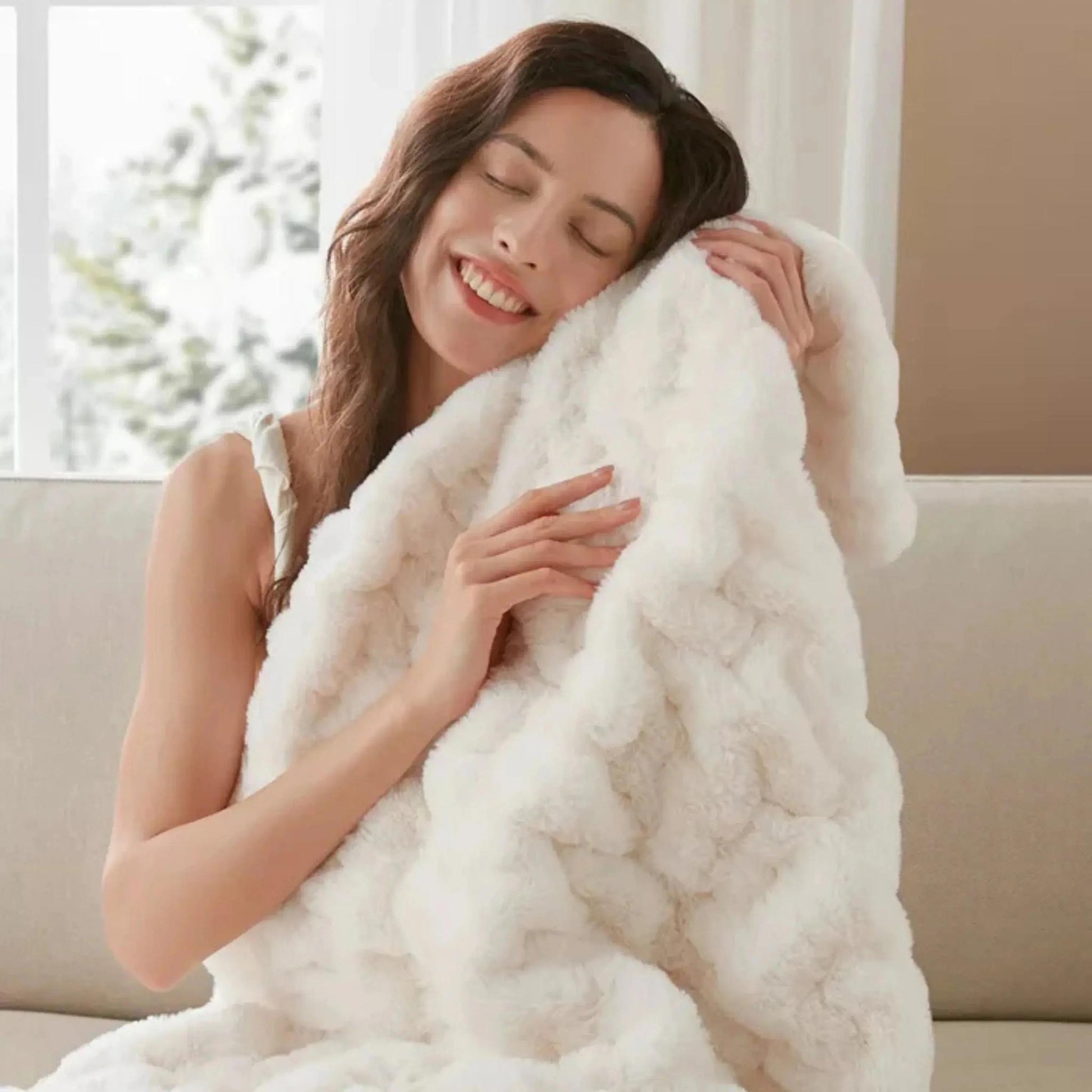 Smiling woman embracing a soft, white ruched faux fur throw blanket, highlighting its cozy texture.