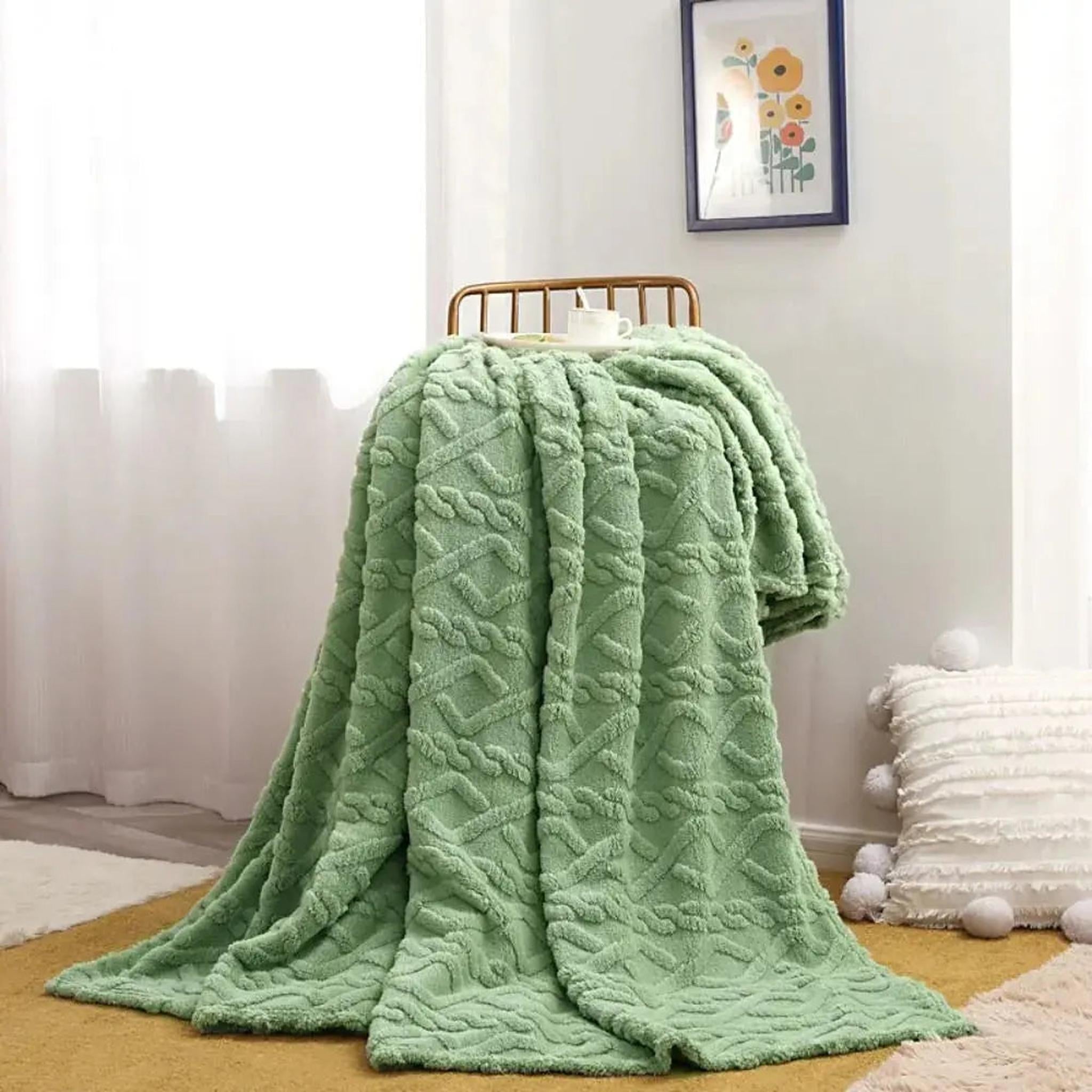 Soft, ruched faux fur throw blanket in light green, draped over a chair, with a textured diamond pattern.