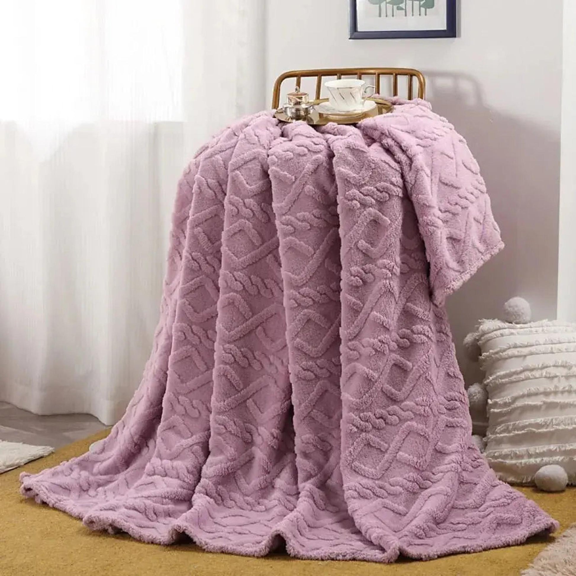 Soft, ruched lavender faux fur throw blanket draped over a chair, with a cup on top.