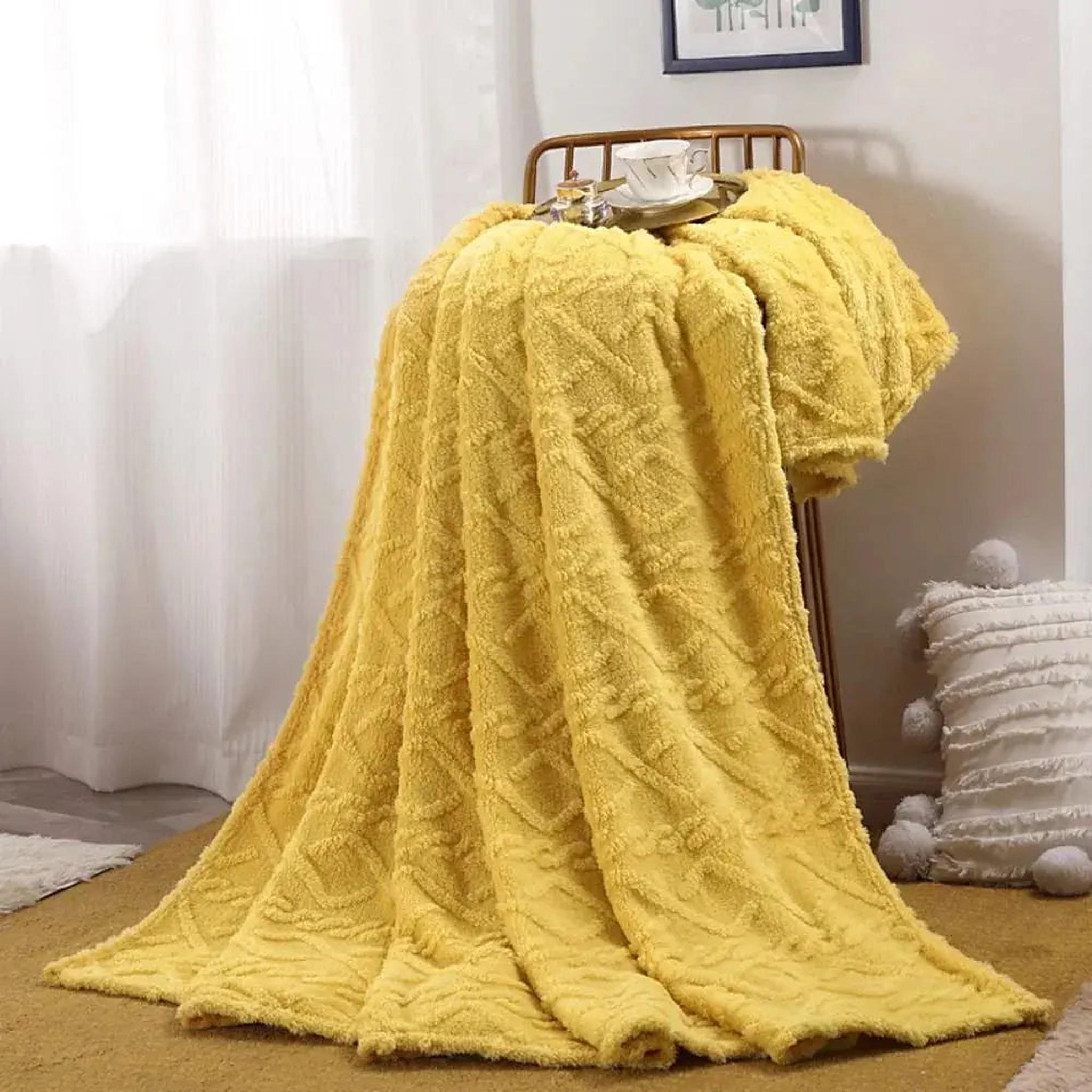 Soft yellow ruched faux fur throw blanket draped over a chair, with a cup on a tray.