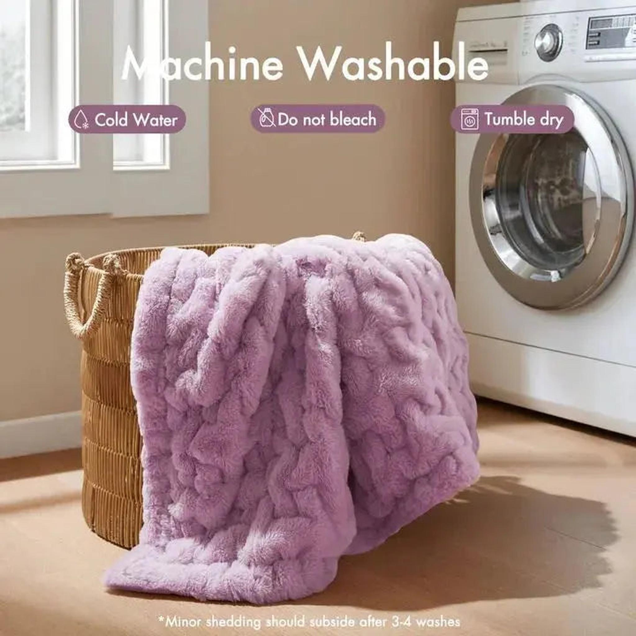 Soft, ruched lavender faux fur throw blanket draped over a wicker laundry basket next to a washing machine.