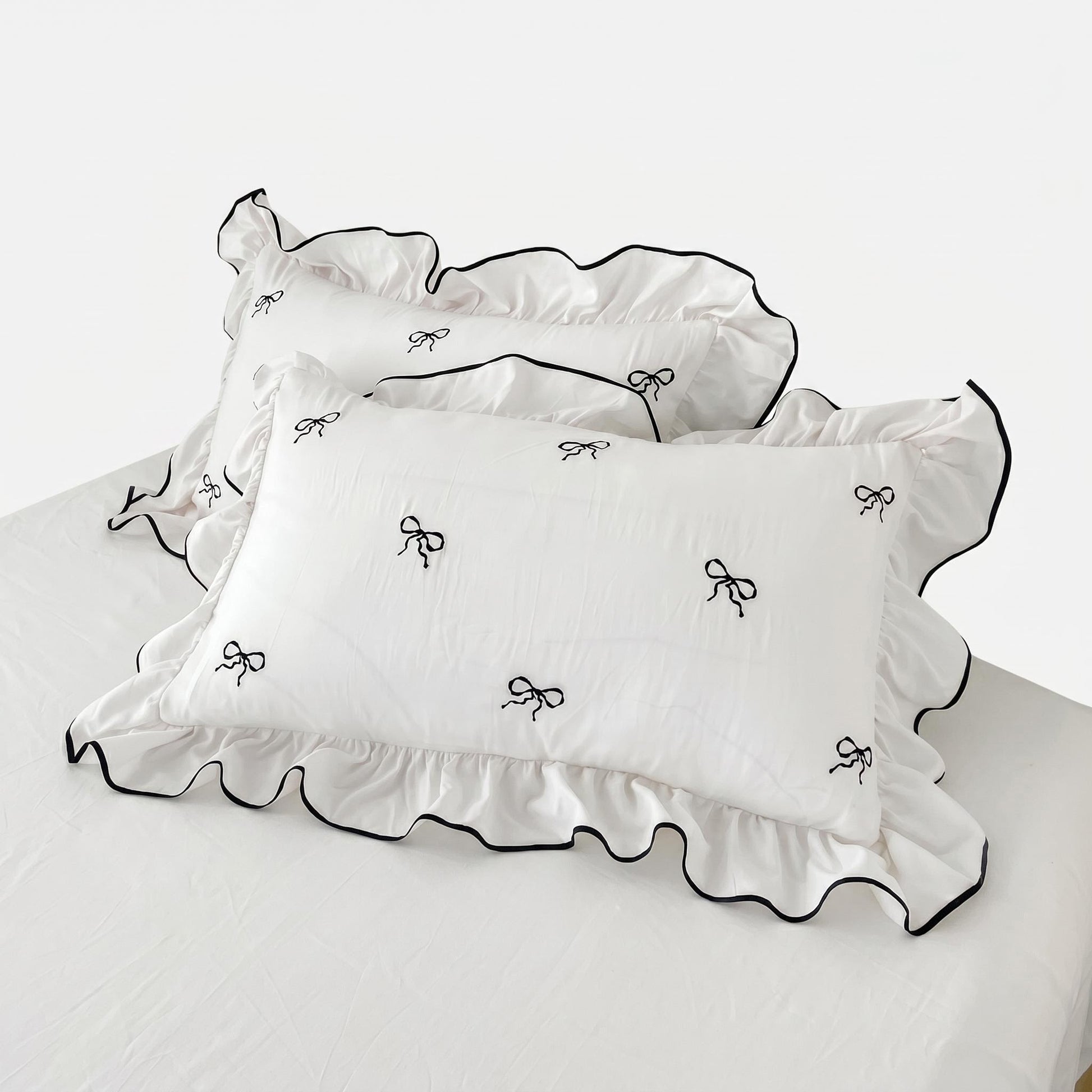 White microfiber pillowcases with black embroidered bows and ruffled edges.