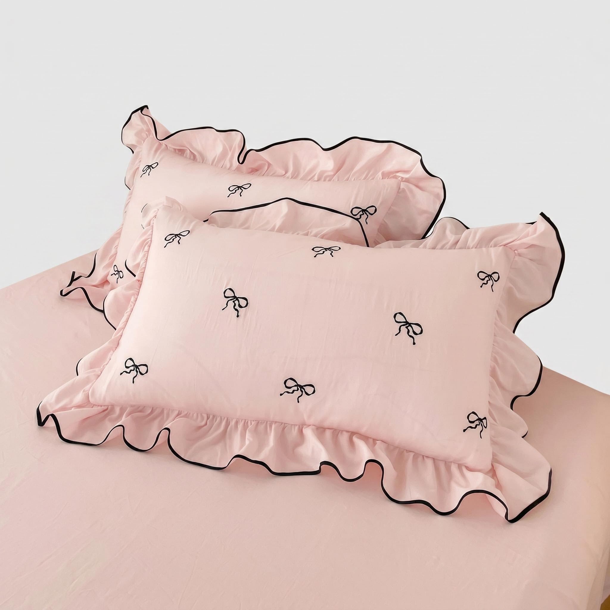 Pink microfiber duvet cover set with black embroidered bows and ruffled edges.