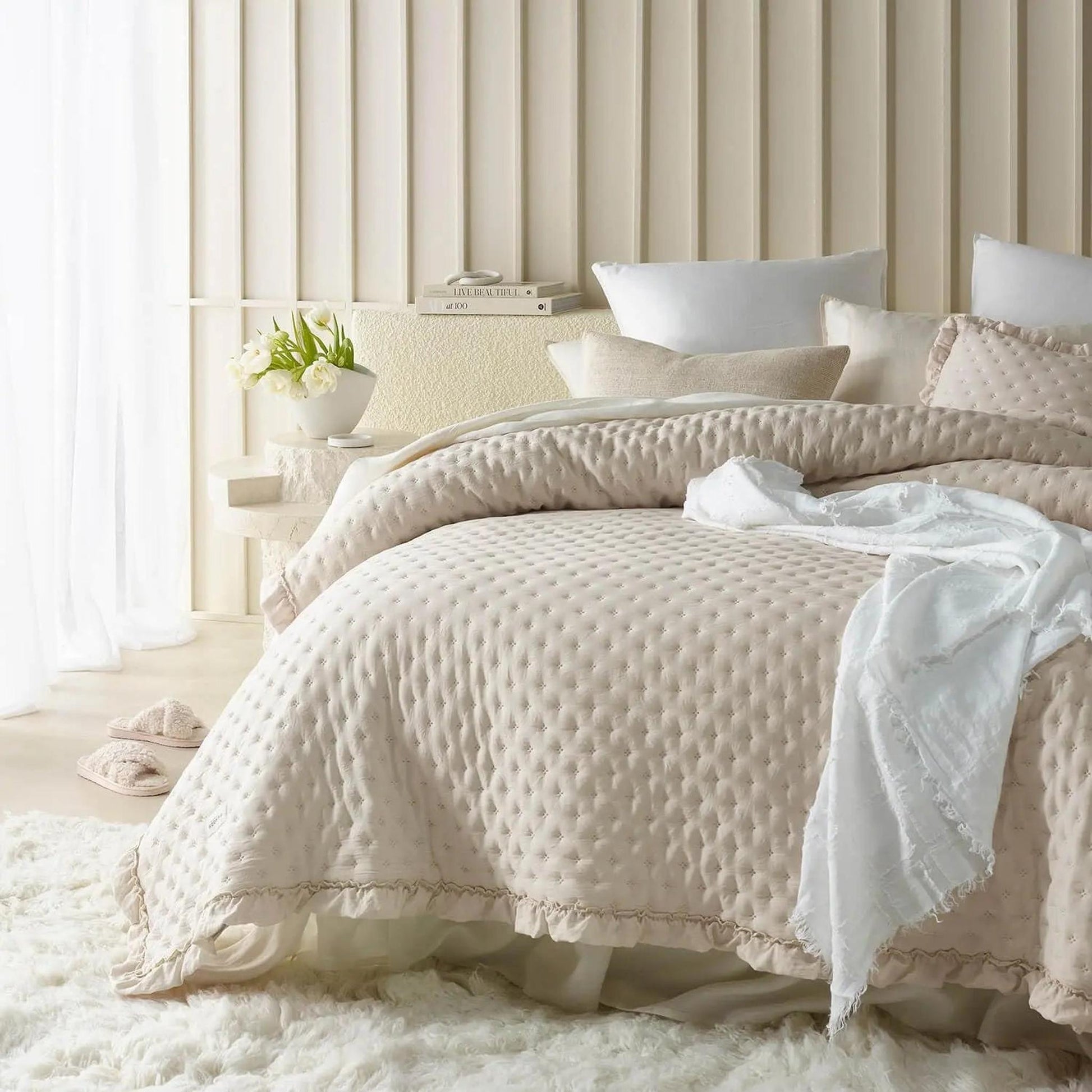 Lightweight beige ruffle mattress cover quilt with scalloped edge on a bed with white pillows.