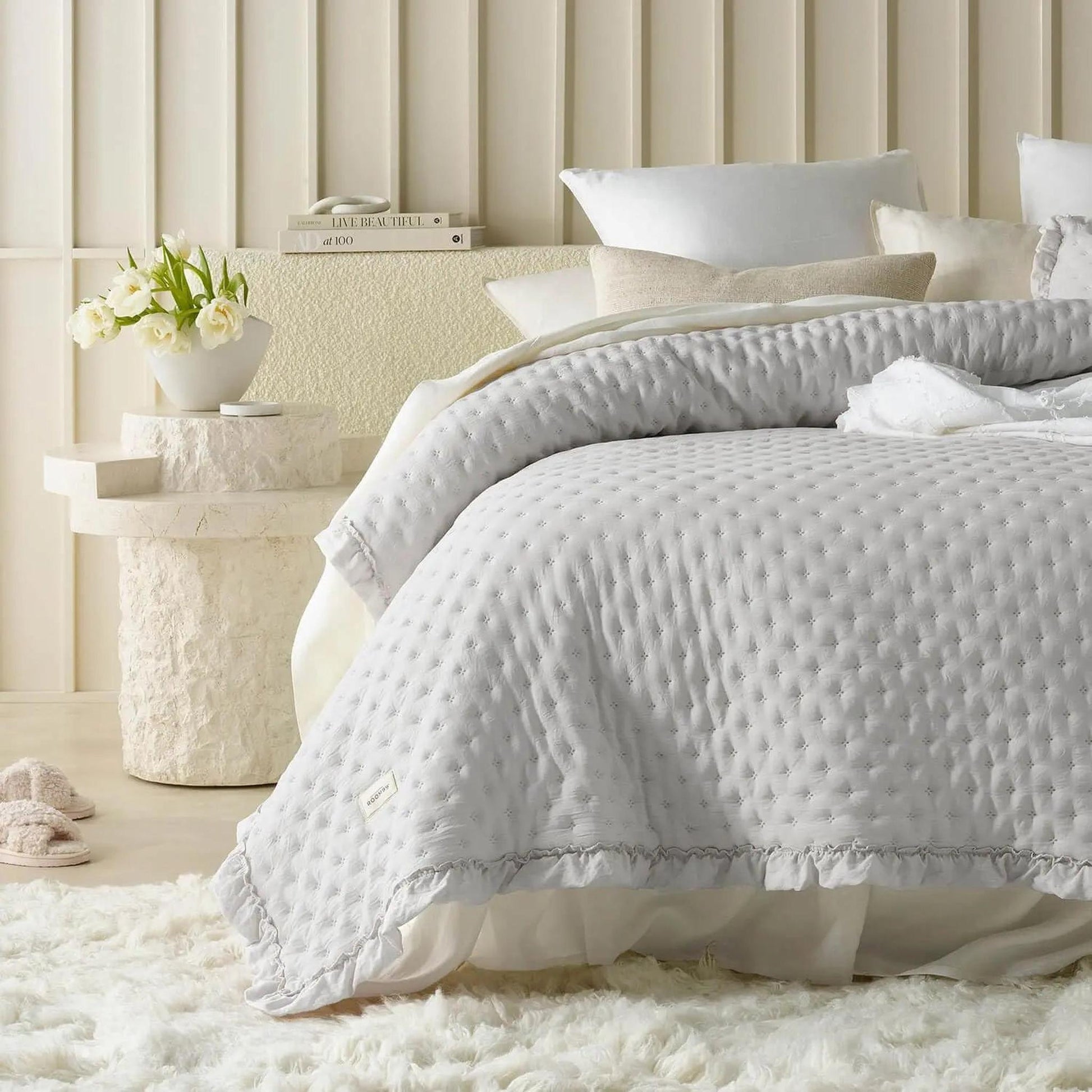 Light gray ruffle mattress cover quilt with scalloped edge on a bed with white pillows.