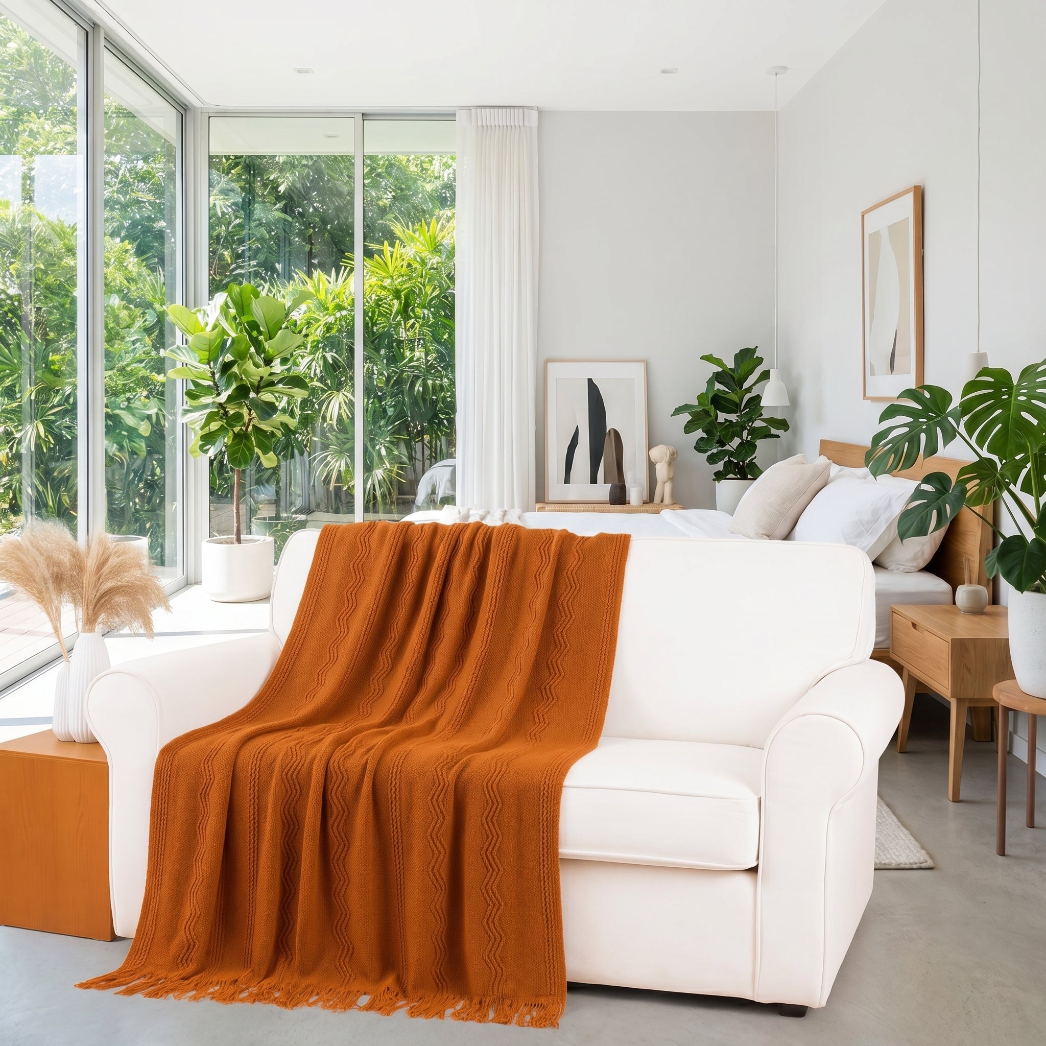 Burnt orange knitted throw blanket draped over a white sofa in a bright, modern living space.