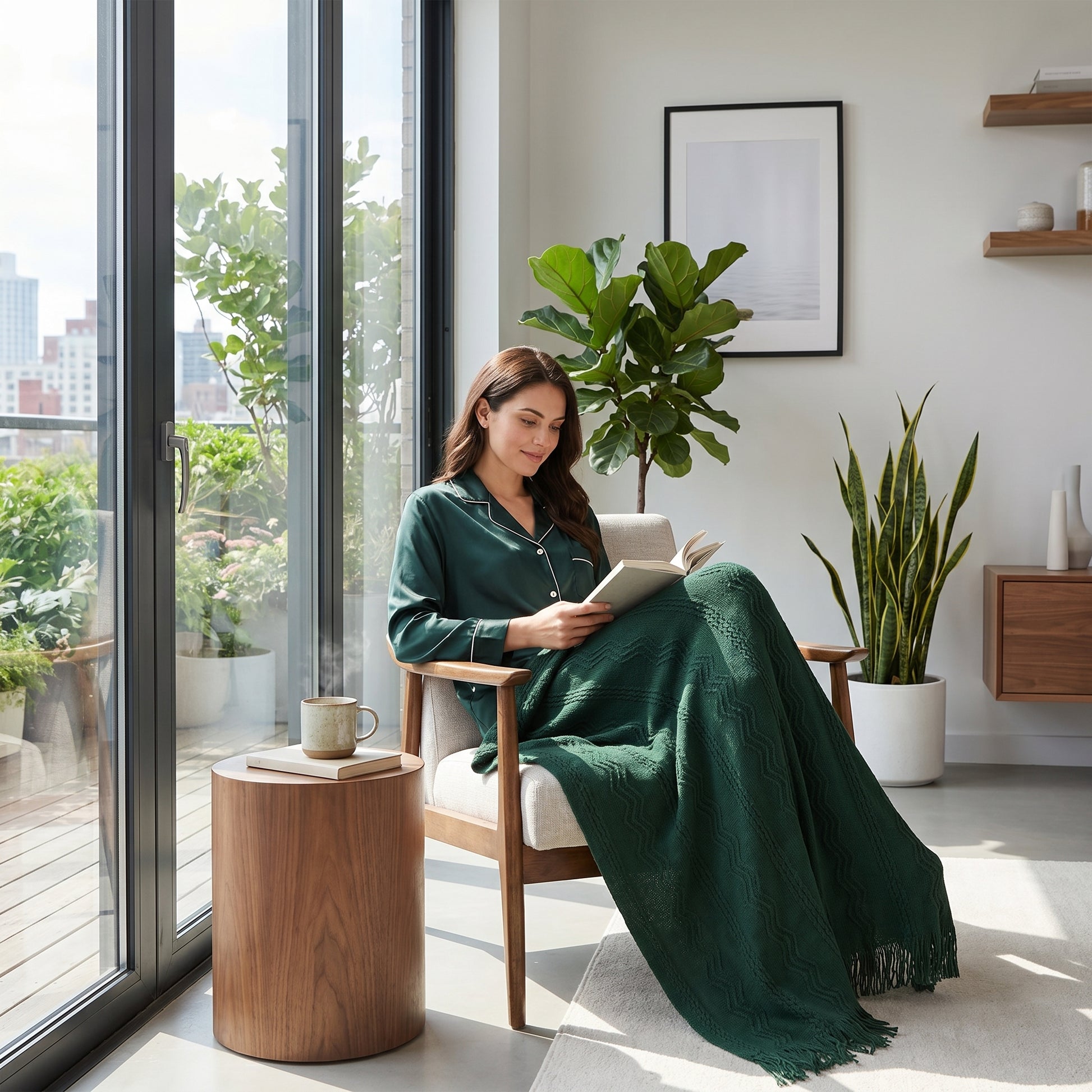 Woman relaxing in a chair, covered by a sage green knitted throw blanket with a plaid pattern.
