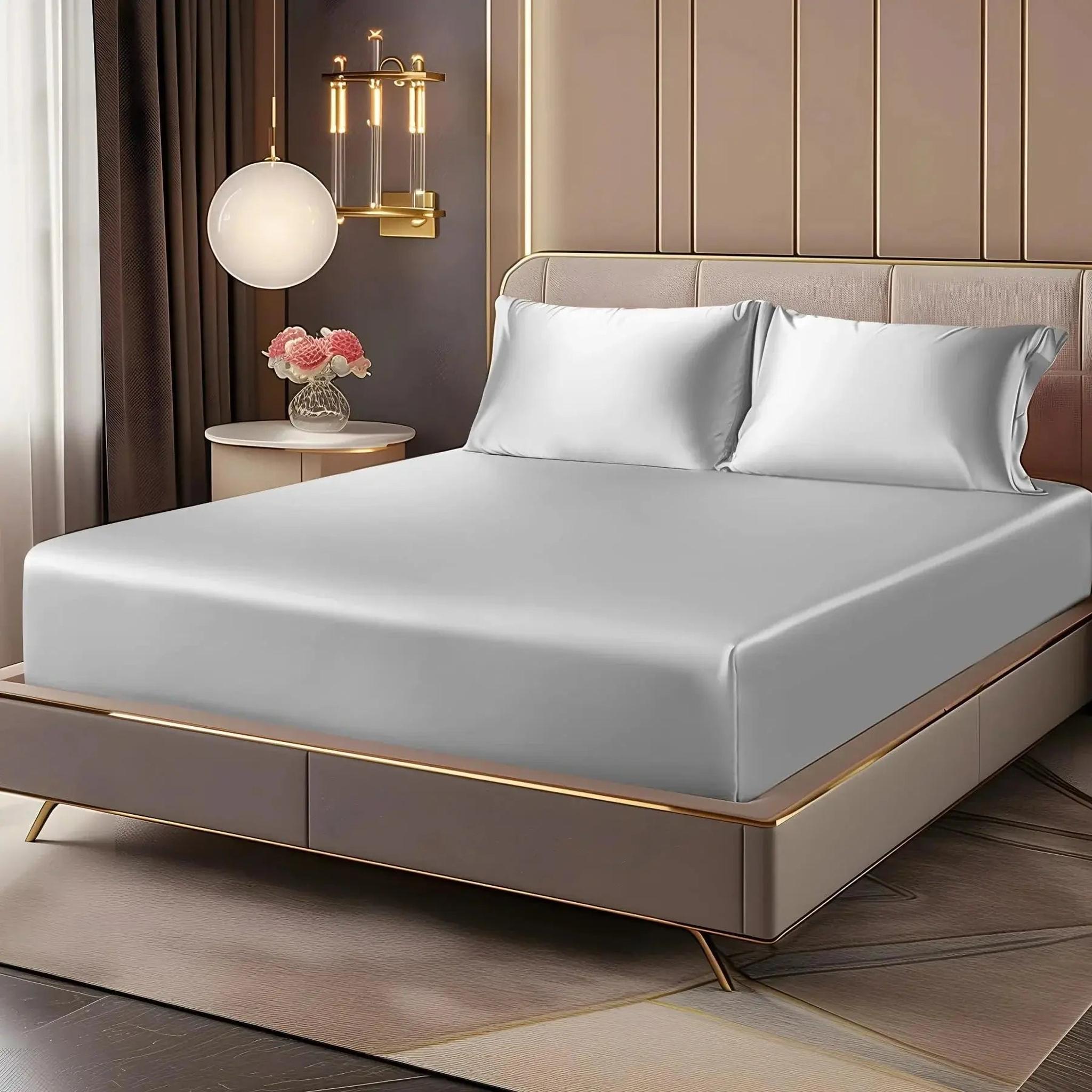 Light gray satin fitted sheet set with two pillowcases on an elegant bed.