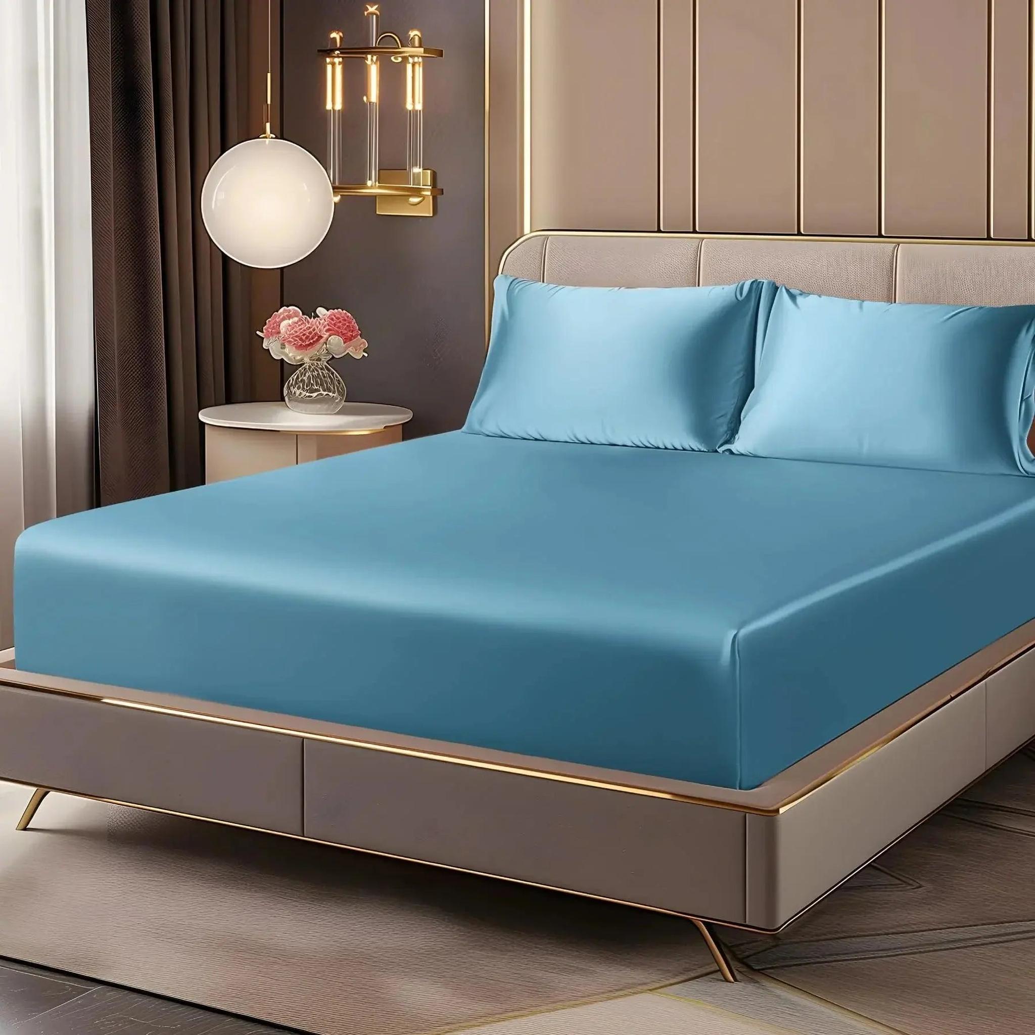 Blue satin fitted sheet set with deep pockets and matching pillowcases on an elegant bed.