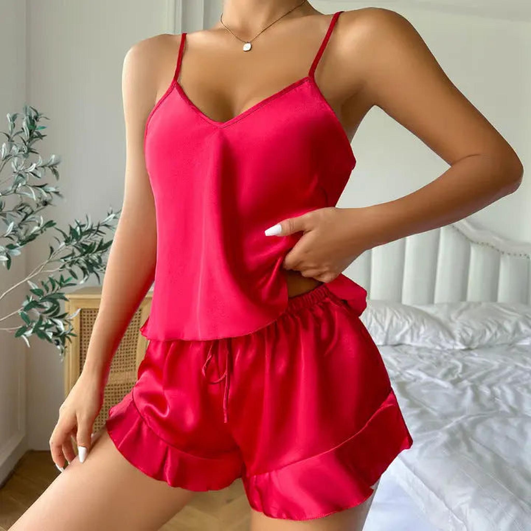 Woman wearing a bright red satin cami pajama set with a V-neck top and ruffled hem shorts.