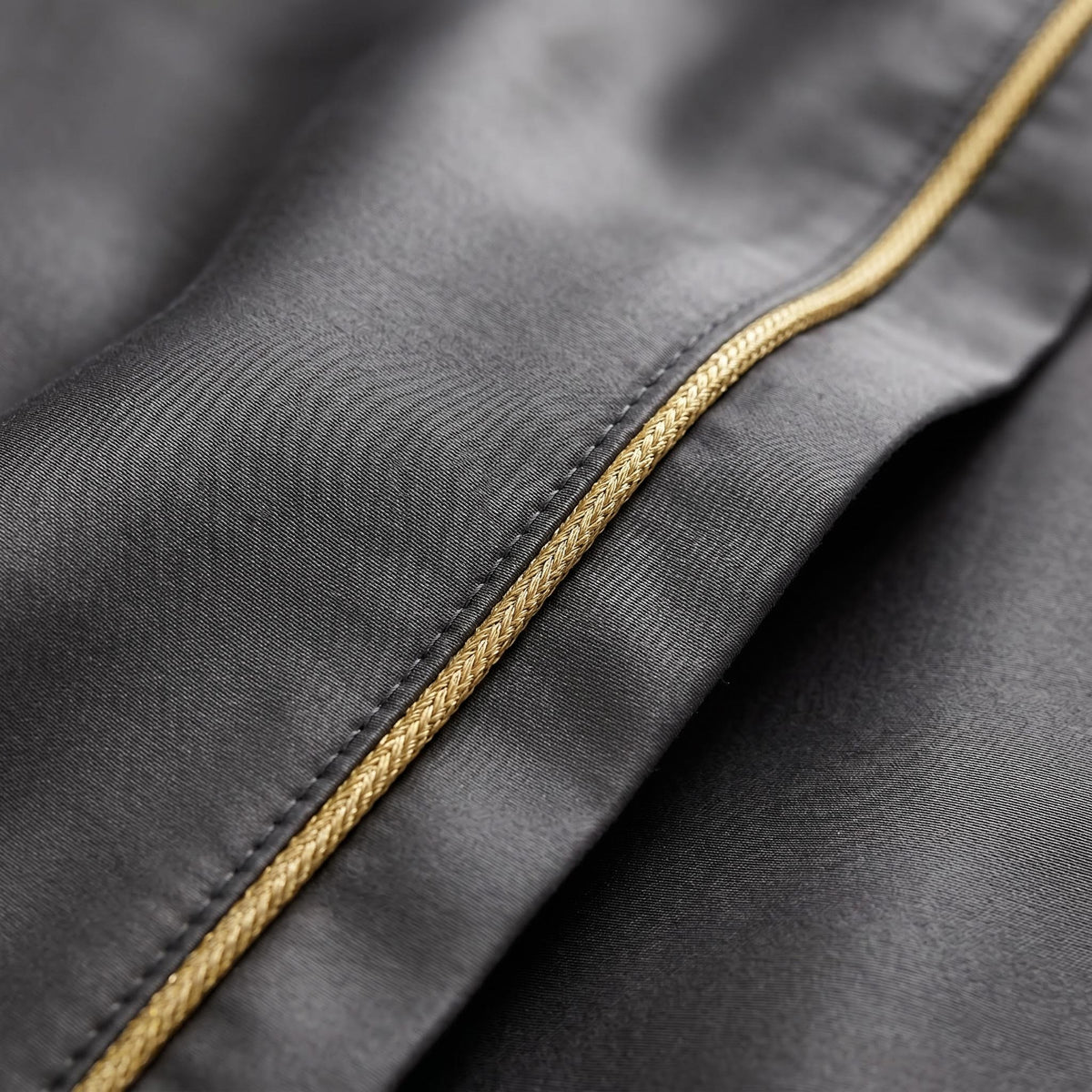 Close-up of a charcoal grey Egyptian cotton duvet cover featuring elegant gold braided embroidery trim.