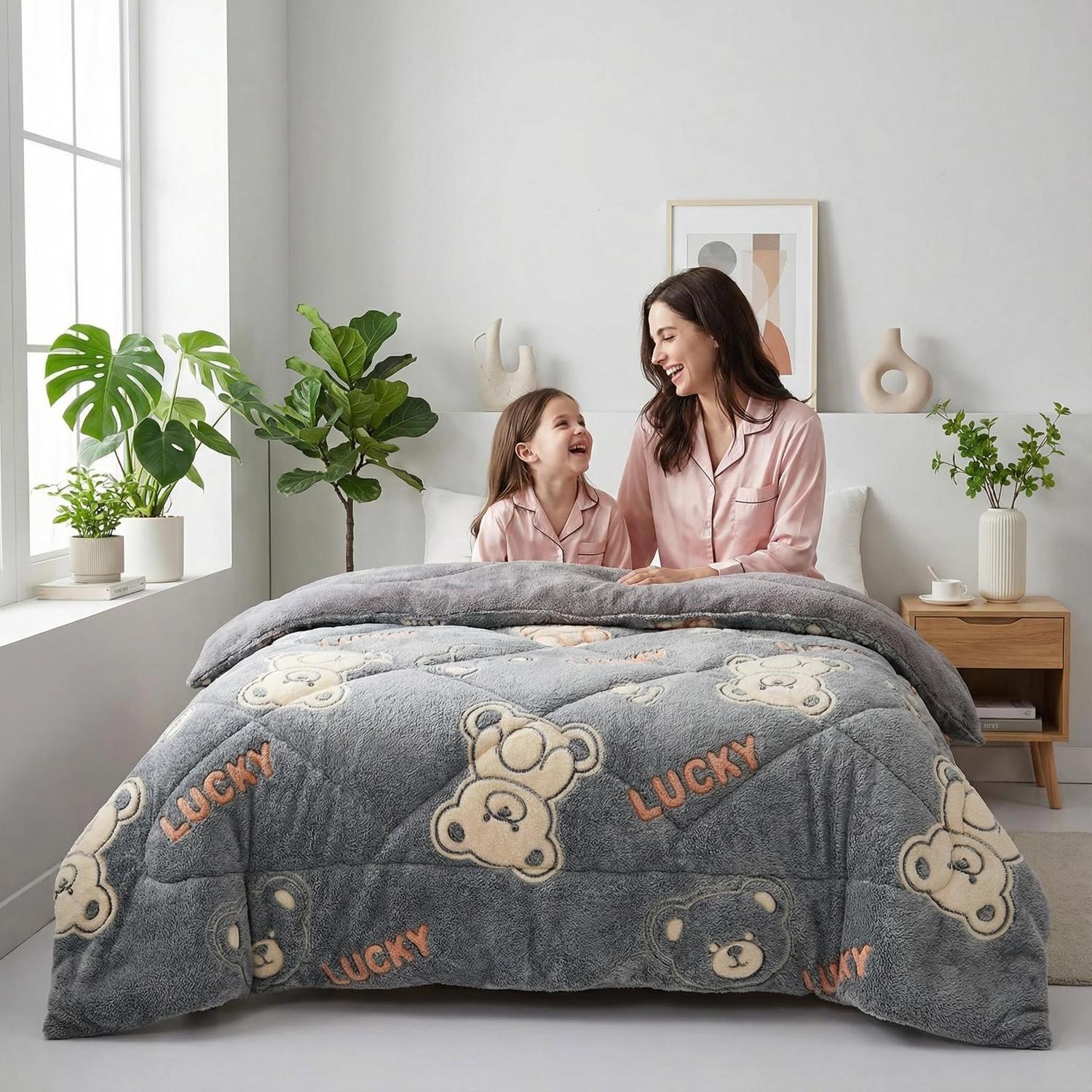 Cozy gray velvet quilt with teddy bear and "LUCKY" print, on a bed with a mother and child.