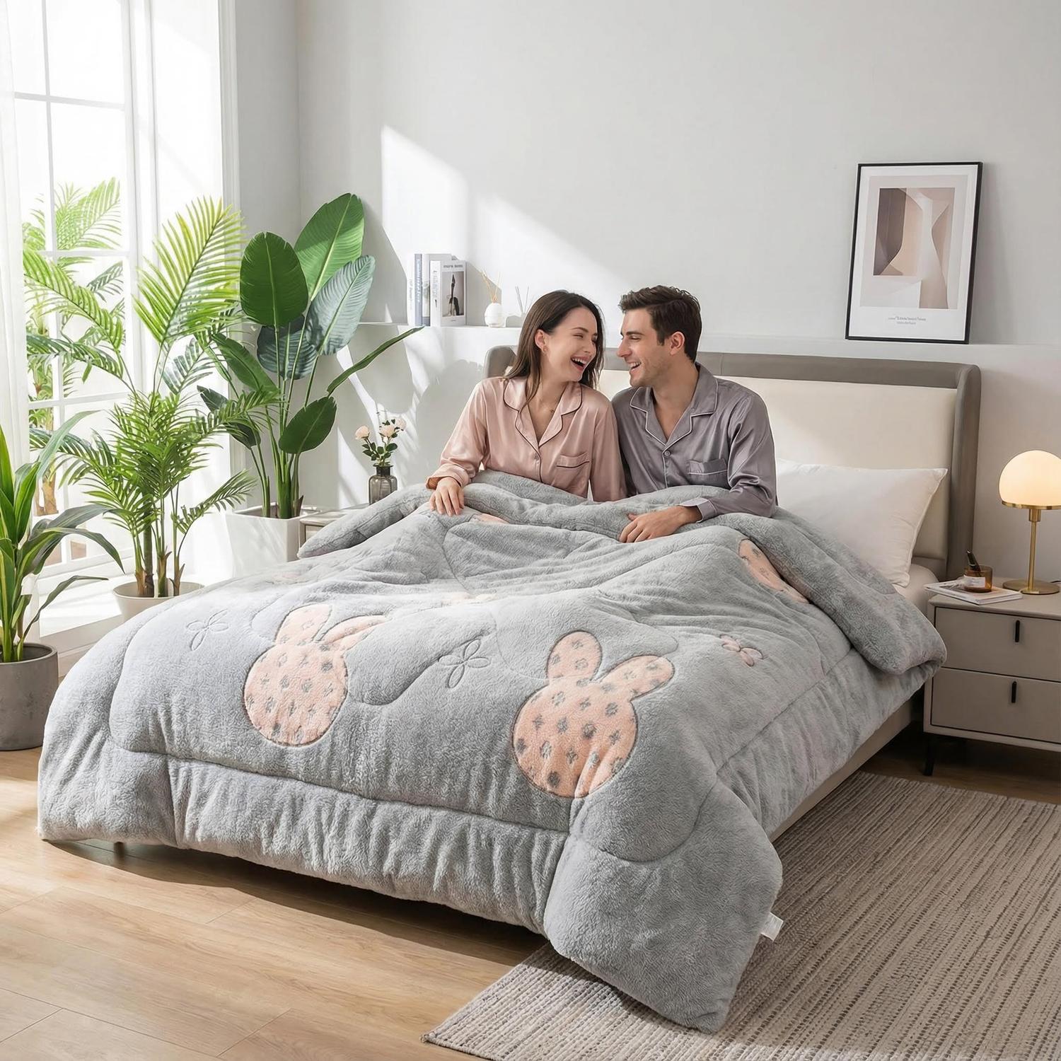 Cozy couple in bed under a thick gray velvet quilt with pink bunny designs.