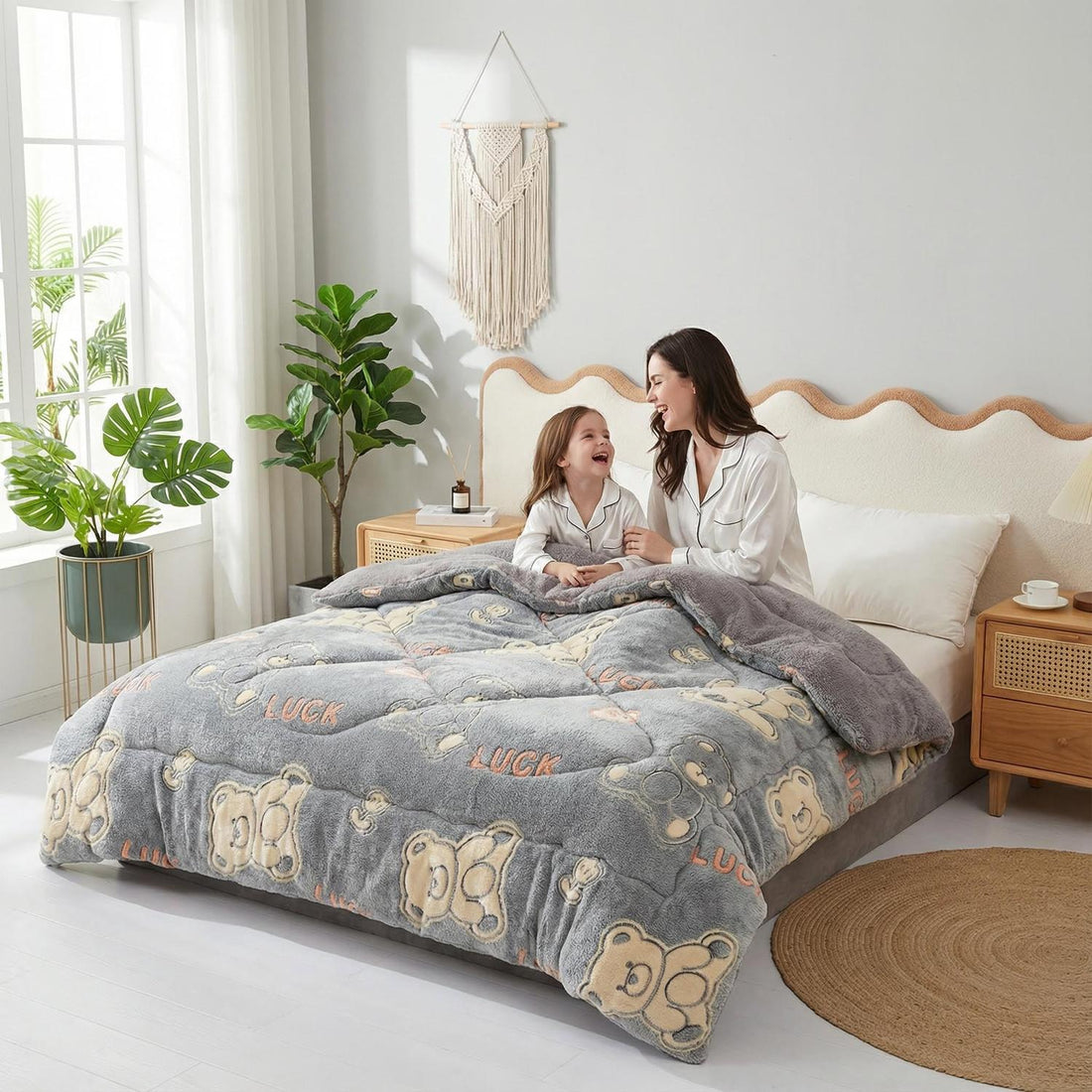 Mother and child on a bed with a gray velvet quilt featuring a teddy bear and "LUCK" pattern.