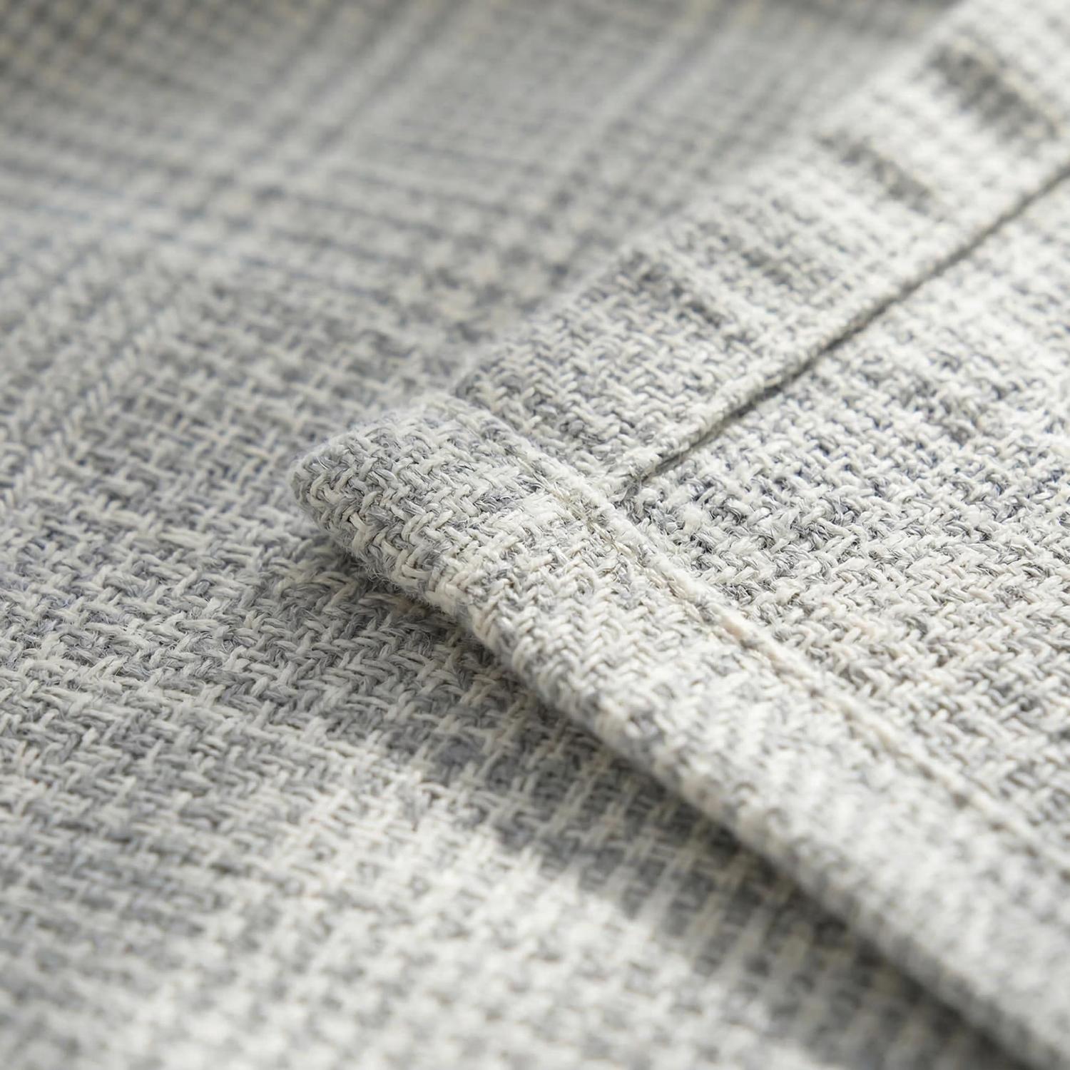 Close-up of a soft, light gray muslin cotton bedspread with a subtle geometric knitted texture.