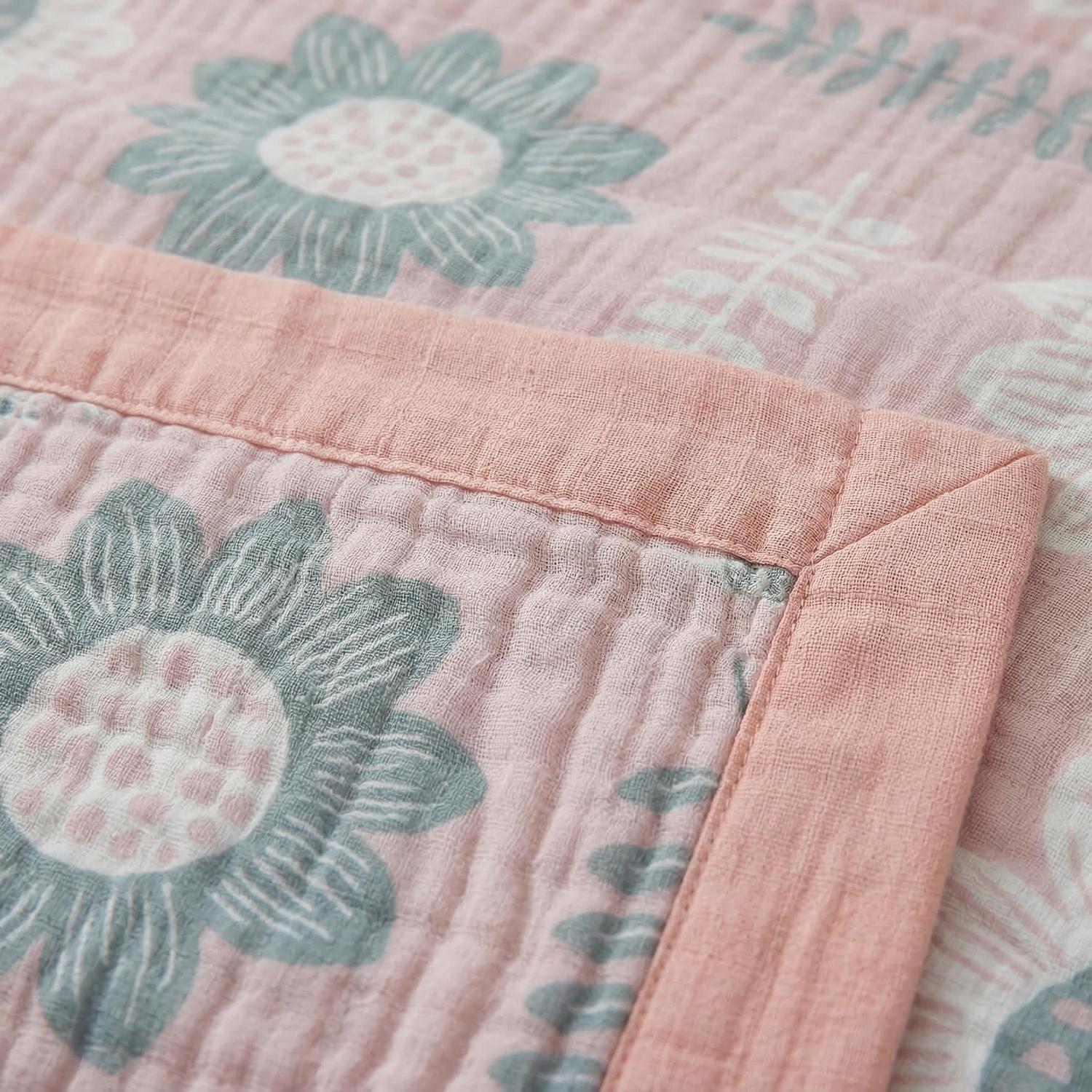 Pink muslin cotton bedspread with grey and white floral pattern and a solid pink border.
