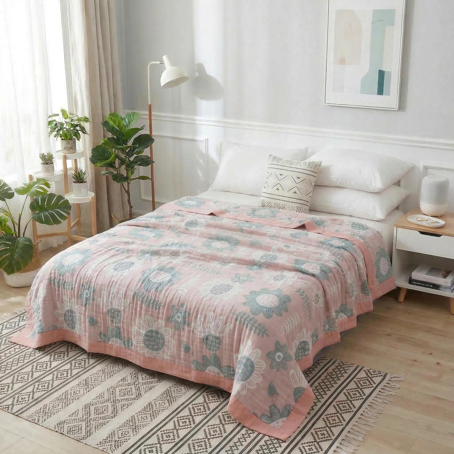 Pink soft cotton bedspread with blue and white floral geometric pattern, draped over a bed in a bright room.