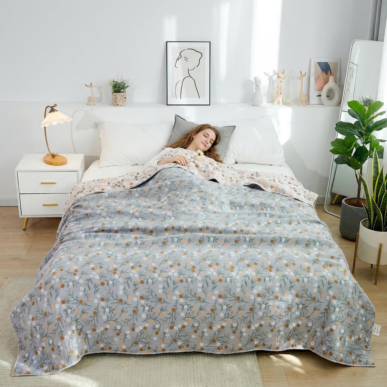Woman sleeping under a soft cotton bedspread with a gray floral and fruit pattern, on a white bed.