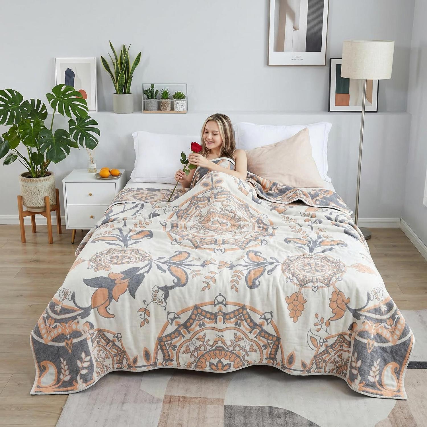 Woman in bed with a soft cotton bedspread, featuring an intricate orange and gray geometric pattern.