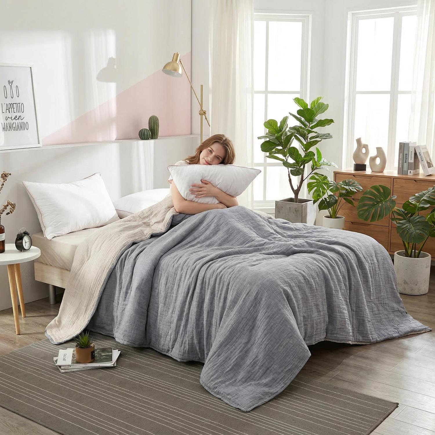 Woman on a bed with a gray and beige soft cotton bedspread, geometric knitted texture.