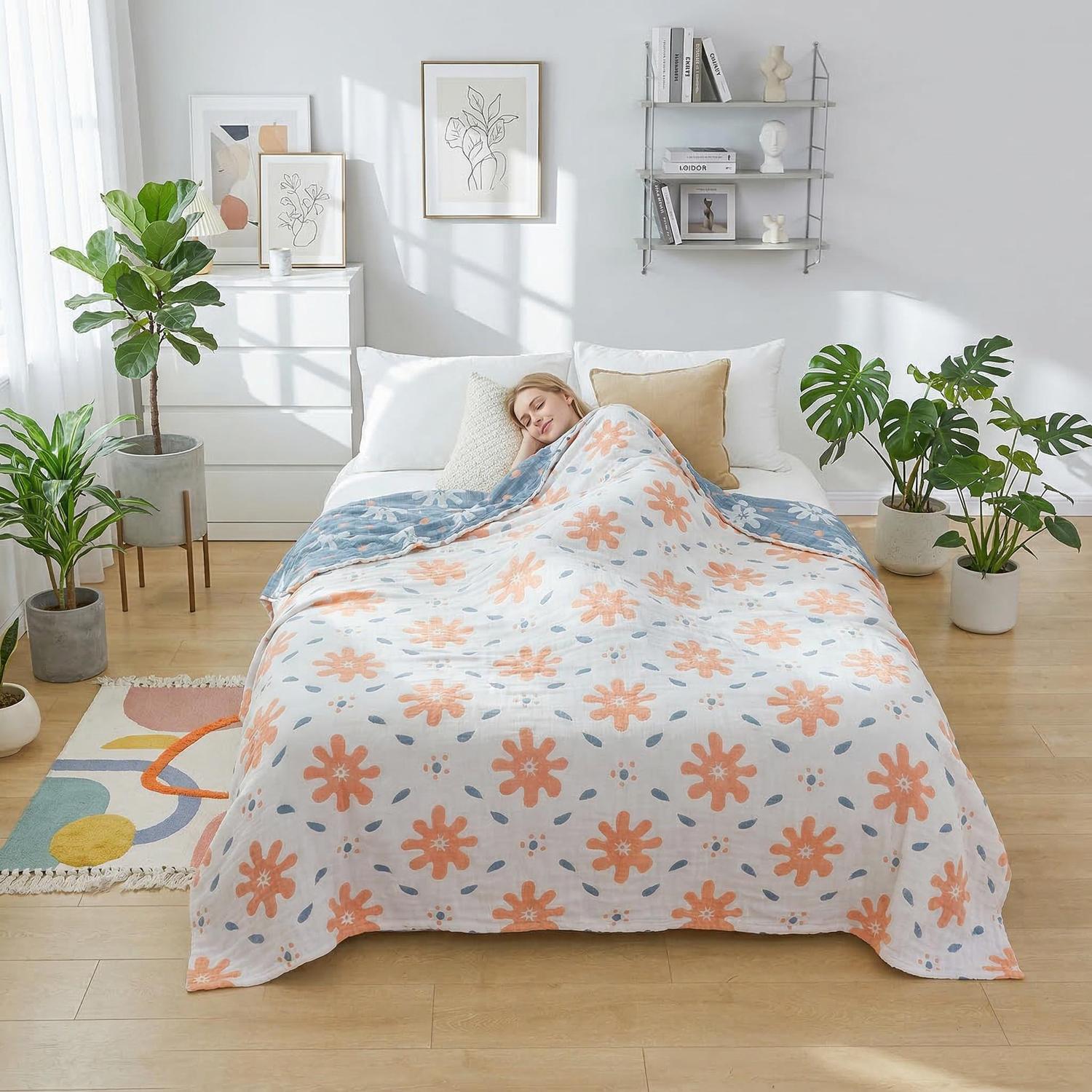 Woman sleeping under a soft cotton summer quilt blanket with orange floral and blue geometric patterns.