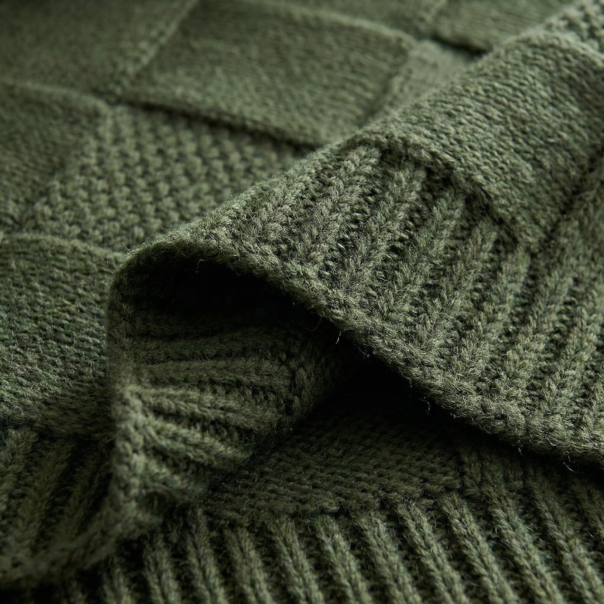 Close-up of a soft, dark green knitted cotton blanket with a textured square pattern.