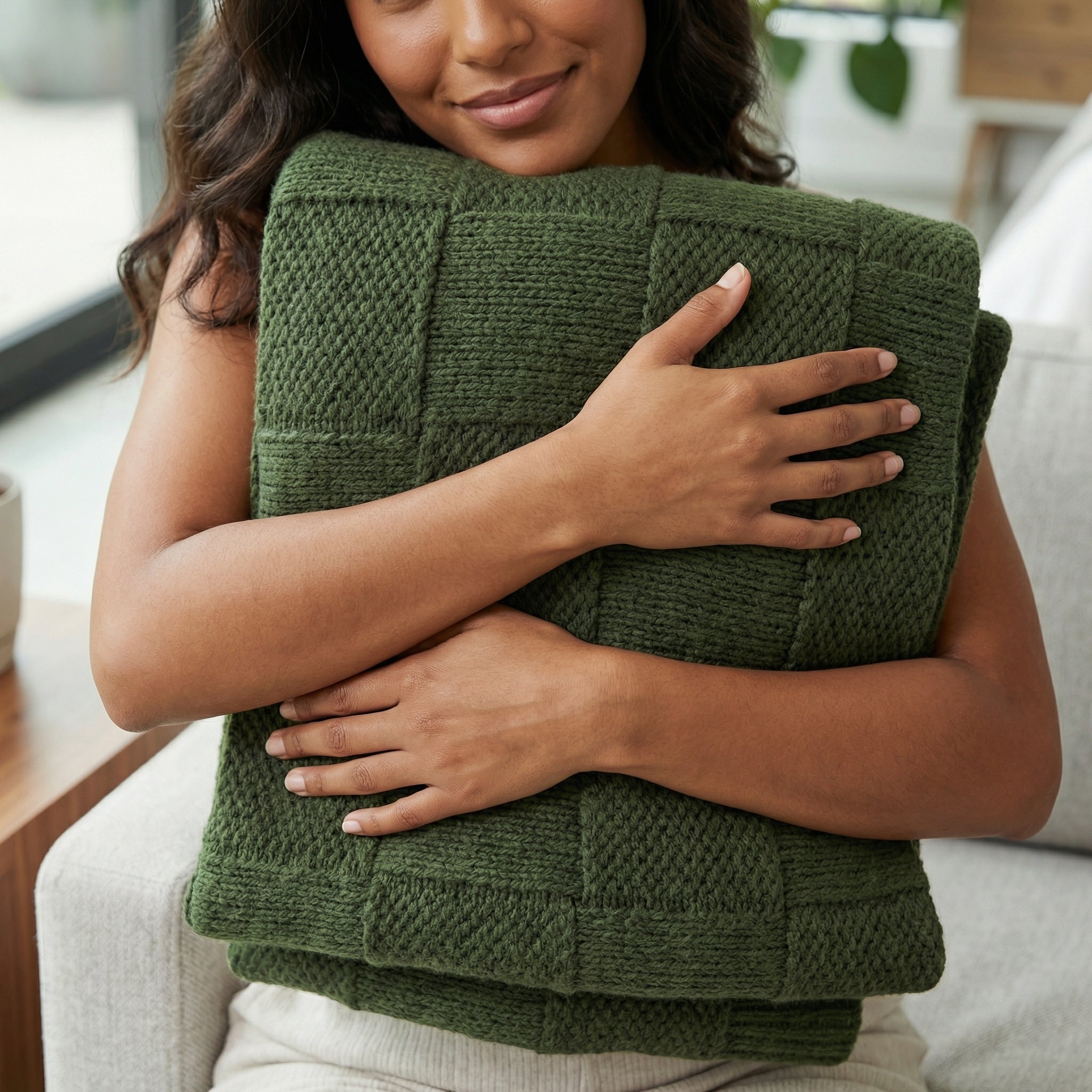 Woman hugging a soft, forest green knitted cotton blanket with a basketweave texture.