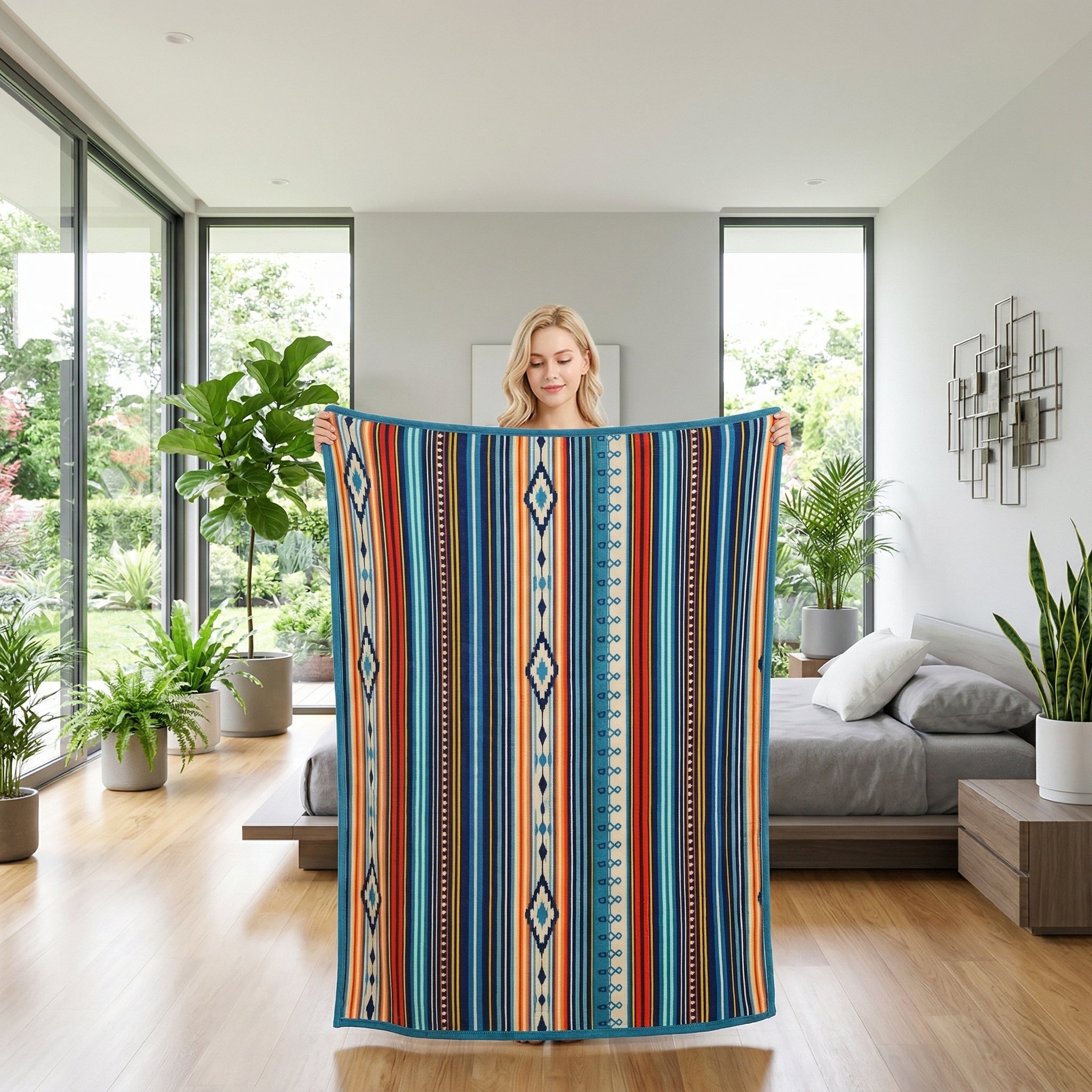 Blonde woman holding a Solaya Boho Throw Blanket with vibrant blue, orange, and red striped patterns in a modern bedroom.