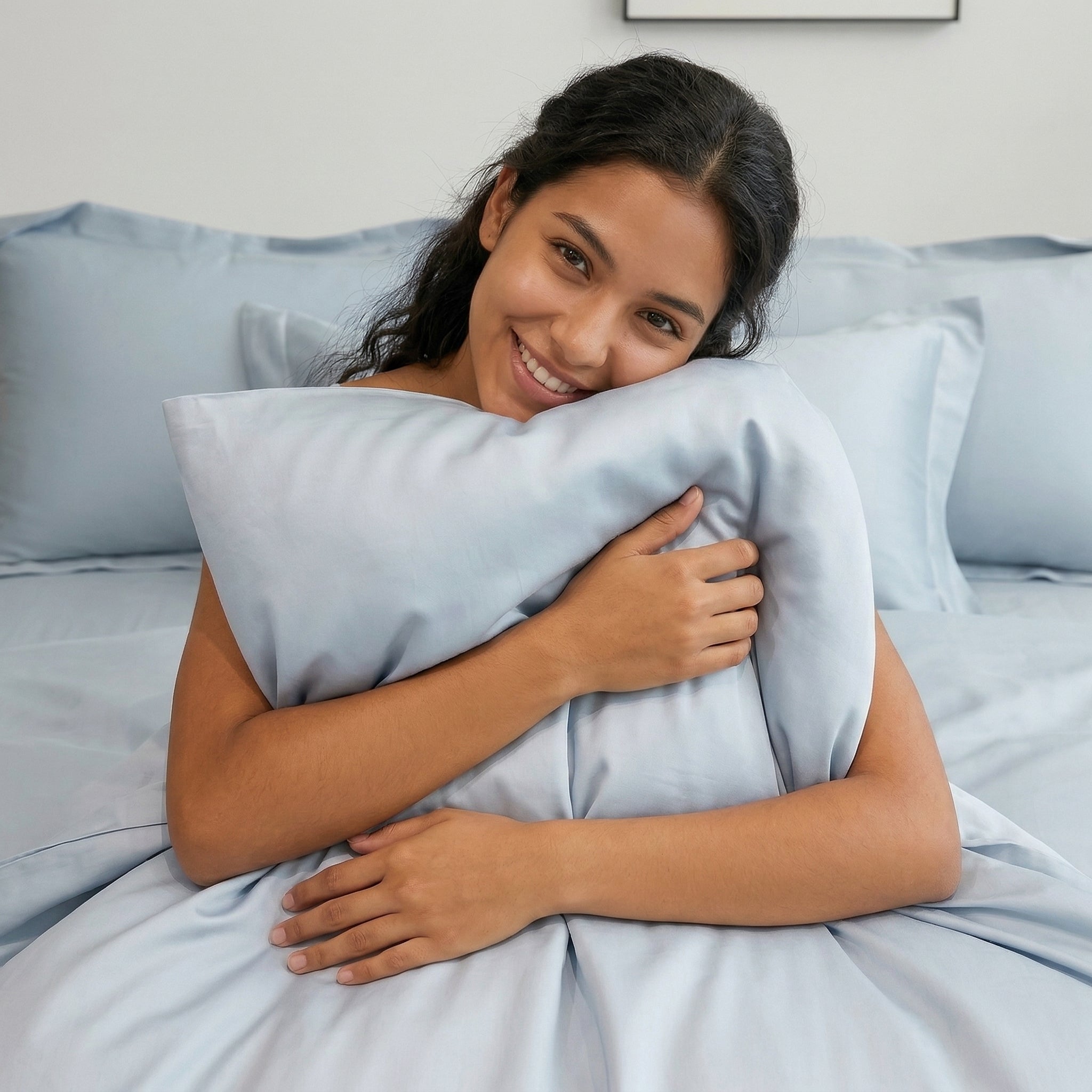 Smiling woman hugging a soft, light blue solid color cotton duvet cover bedding set.