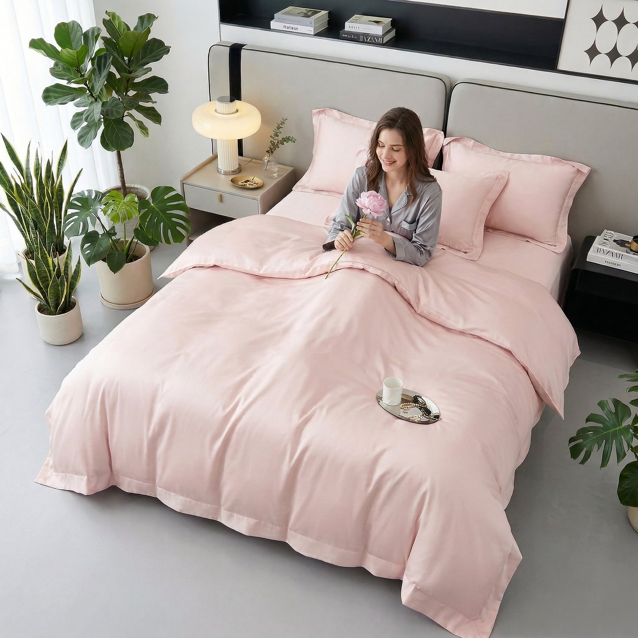 Woman on a bed with a soft pink solid color cotton duvet cover set, holding a flower.
