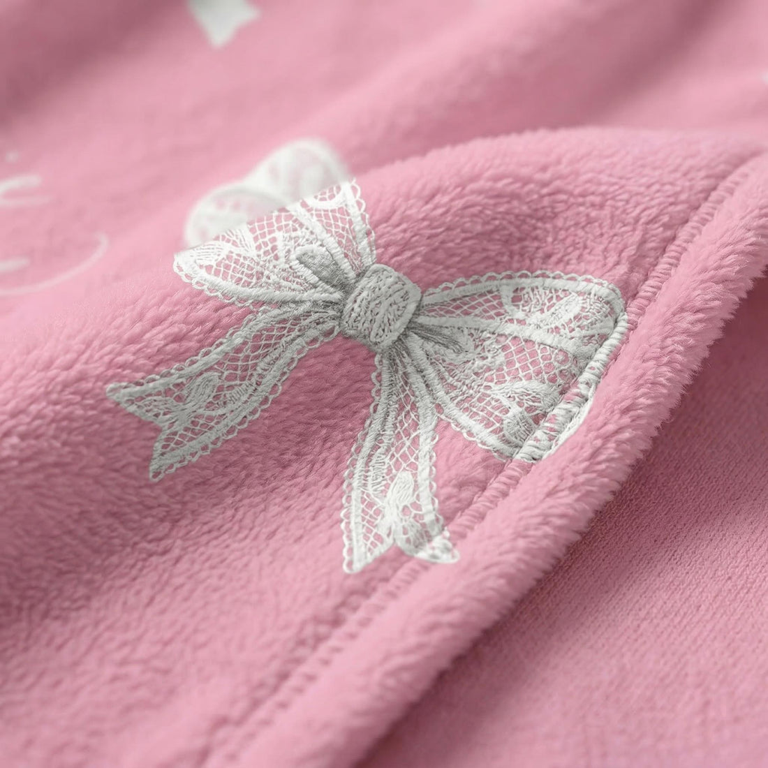 Blonde woman on a sofa, cuddling a white cat under a pink flannel blanket with white bow designs.