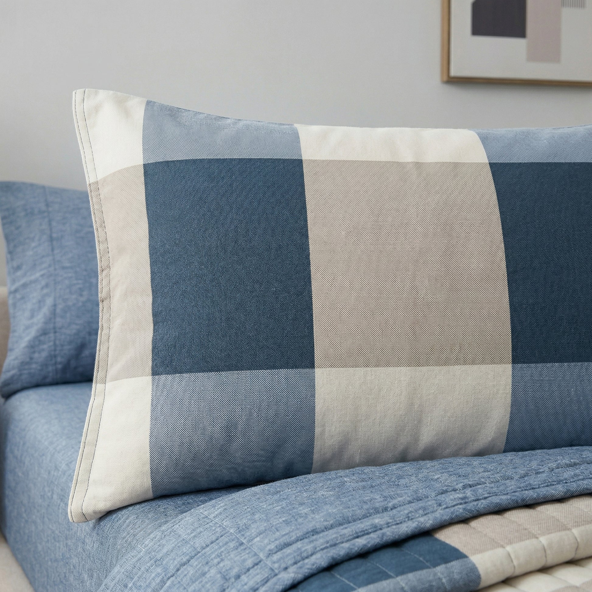 Blue and beige plaid microfiber pillowcase on a bed with a light blue quilted blanket.