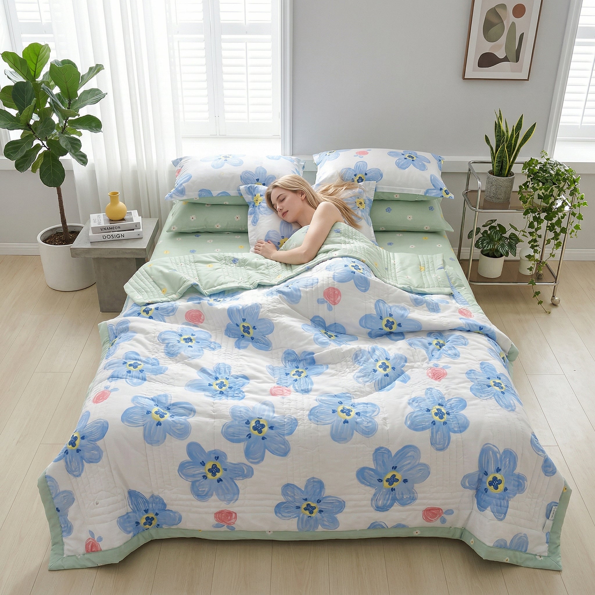 Woman sleeping on a bed with a white quilt featuring large blue floral patterns and light green sheets.