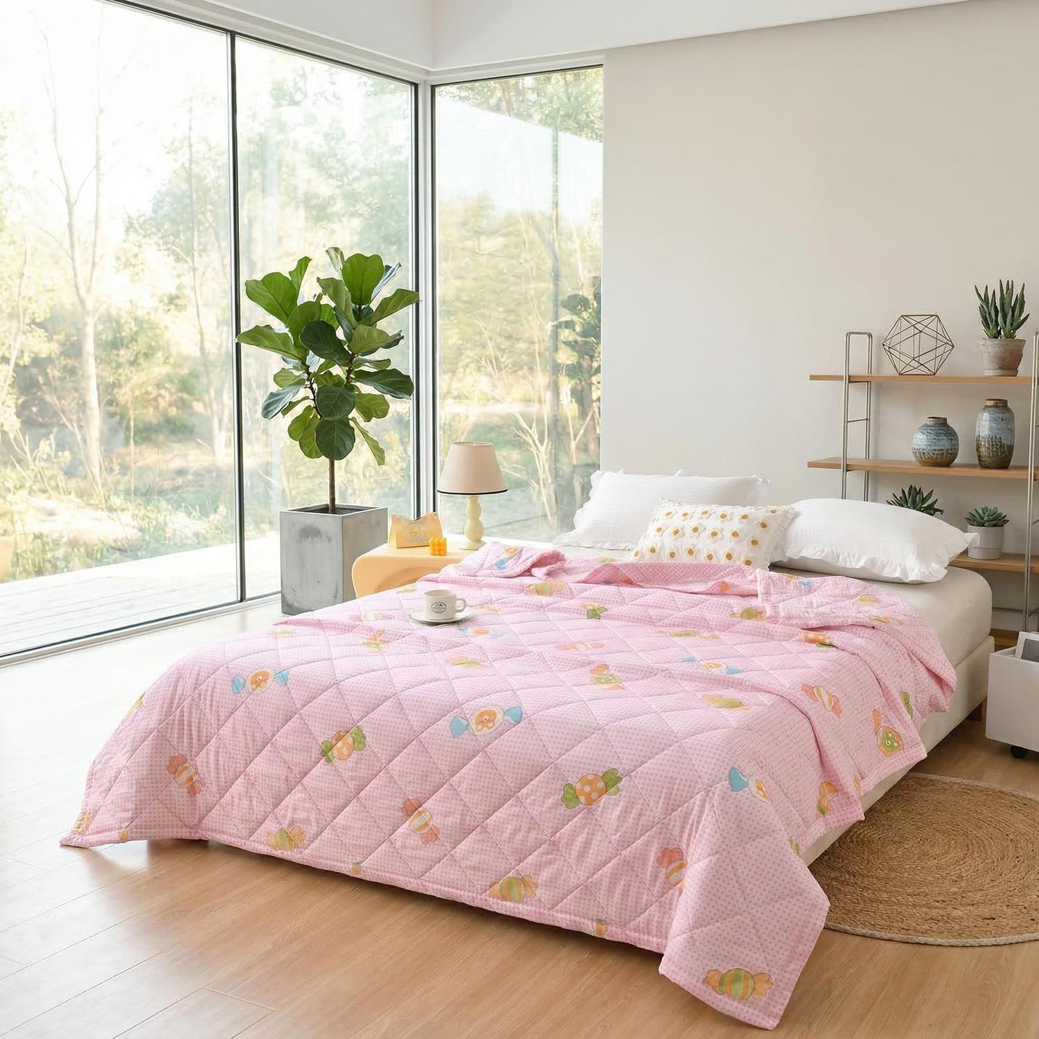 Pink ultrasonic quilted lightweight summer comforter with colorful candy pattern on a bed in a bright room.