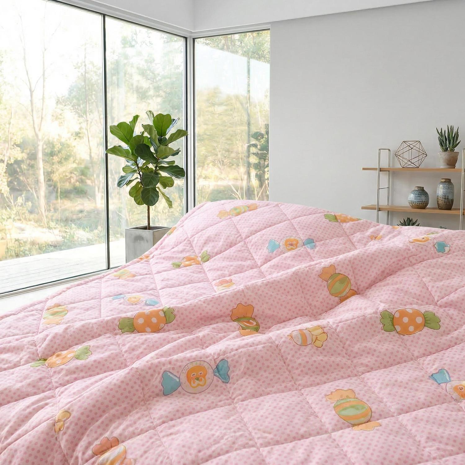Pink lightweight polyester summer comforter with candy pattern and ultrasonic quilted design on a bed.