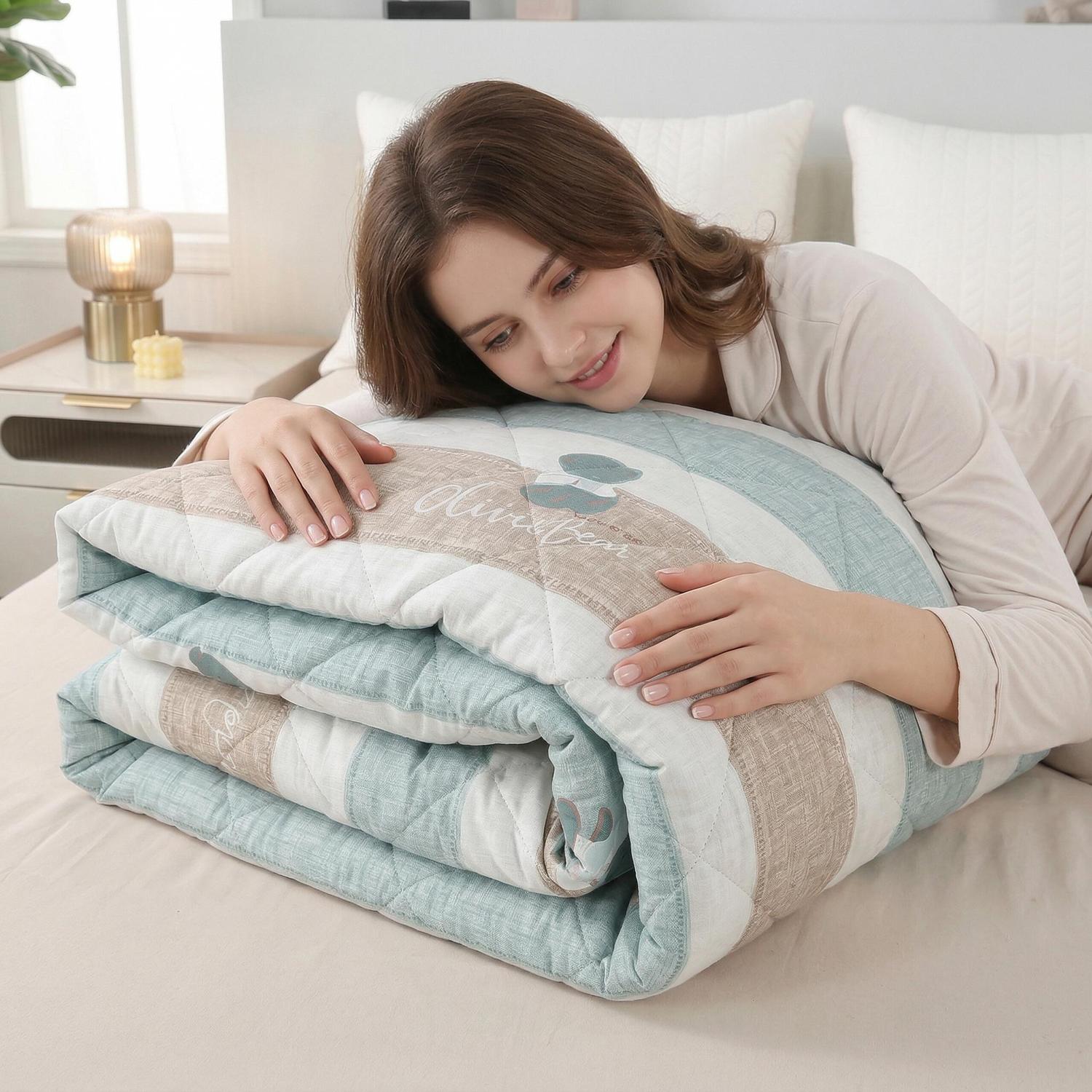 Woman smiling, embracing a folded lightweight summer comforter with blue, white, and beige stripes.