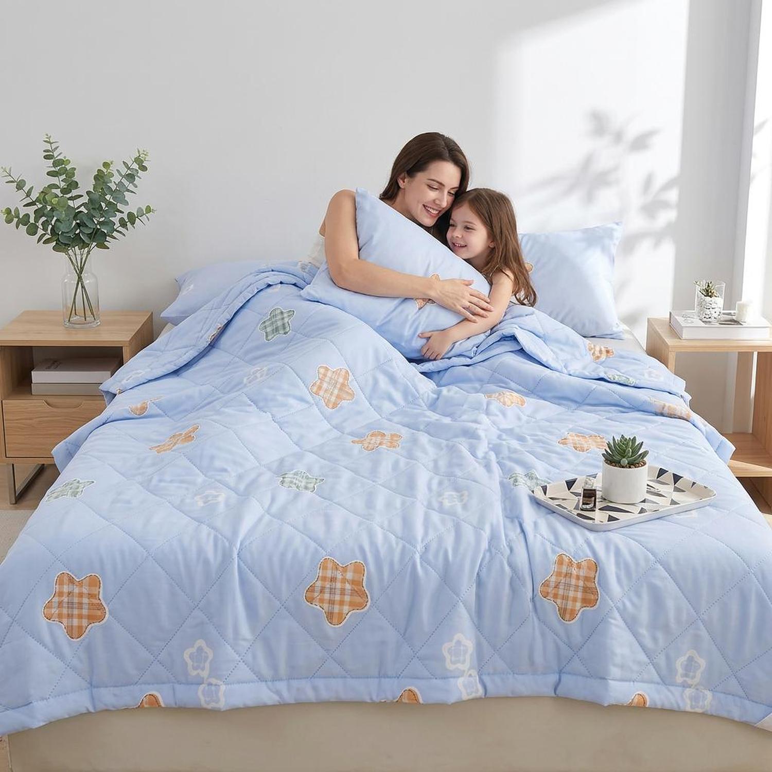 Light blue ultrasonic quilted summer comforter with star patterns, on a bed with a mother and child.