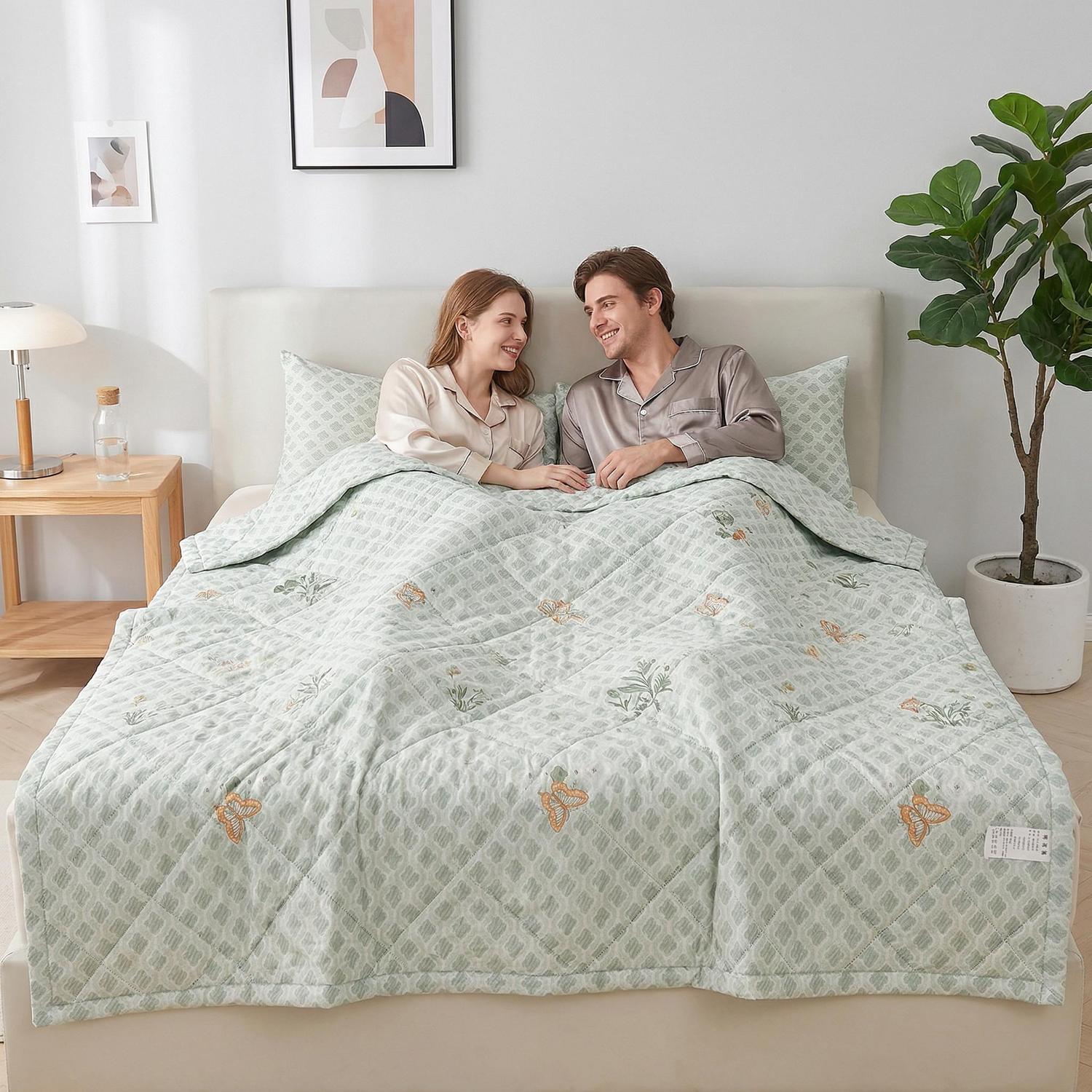 Couple in bed with a light green ultrasonic quilted comforter featuring butterfly and plant embroidery.
