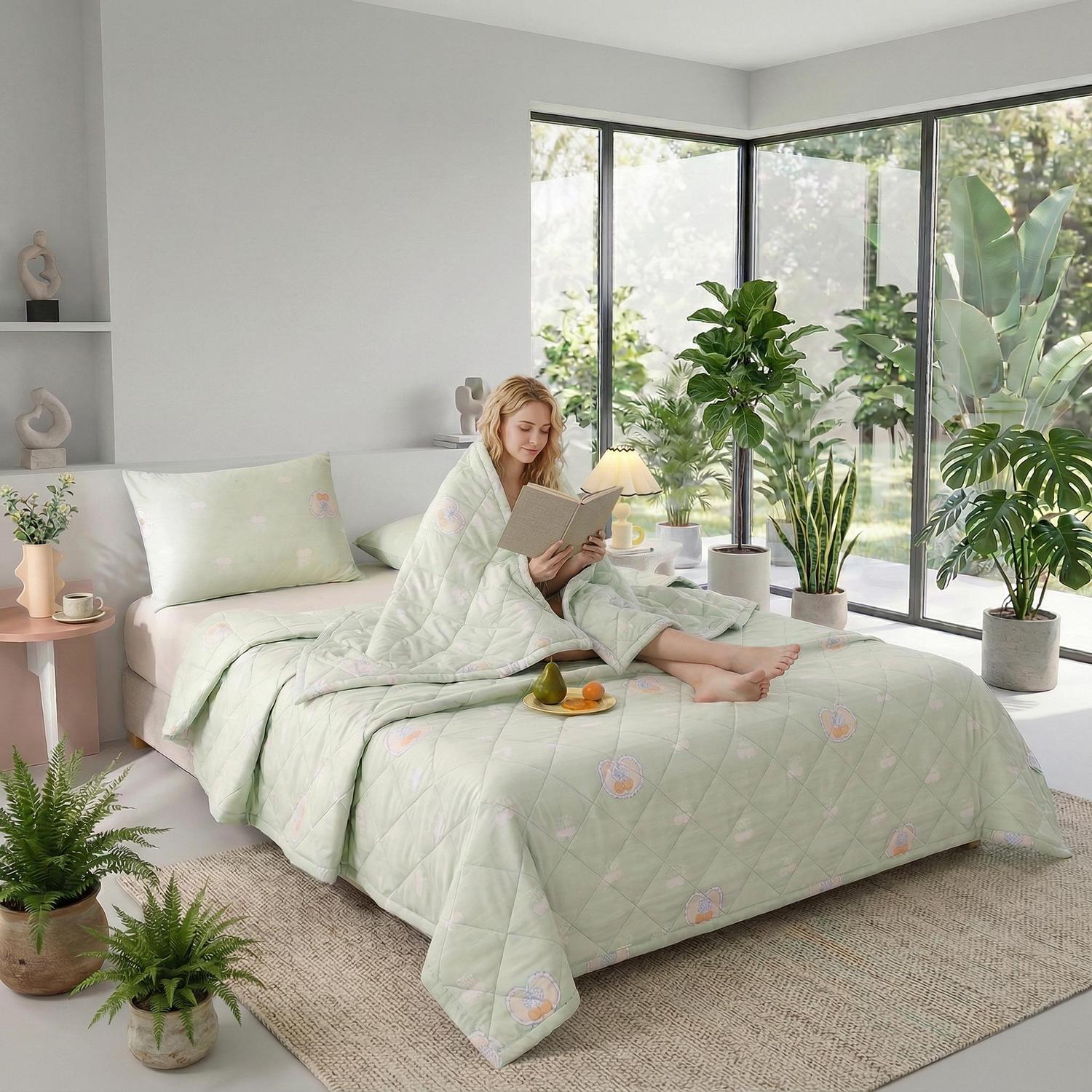 Light green ultrasonic quilted comforter on a bed with a woman reading, surrounded by plants.