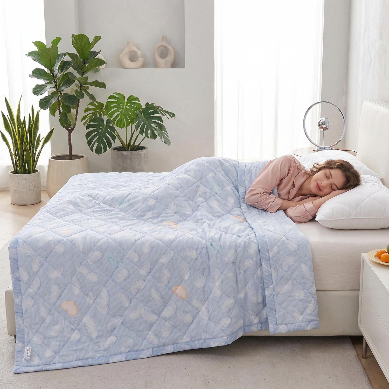 Woman sleeping soundly under a light blue ultrasonic quilted polyester summer comforter with feather patterns.