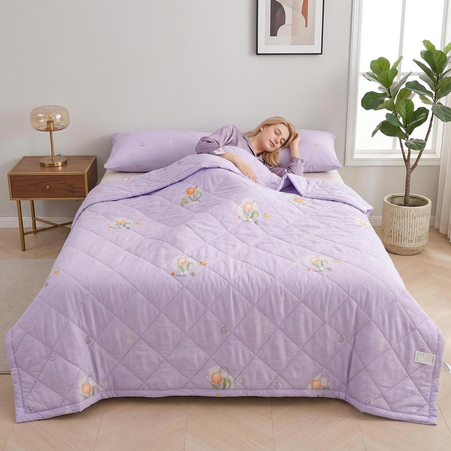 Woman sleeping soundly under a soft, lightweight lavender summer comforter with a subtle floral and quilted design.